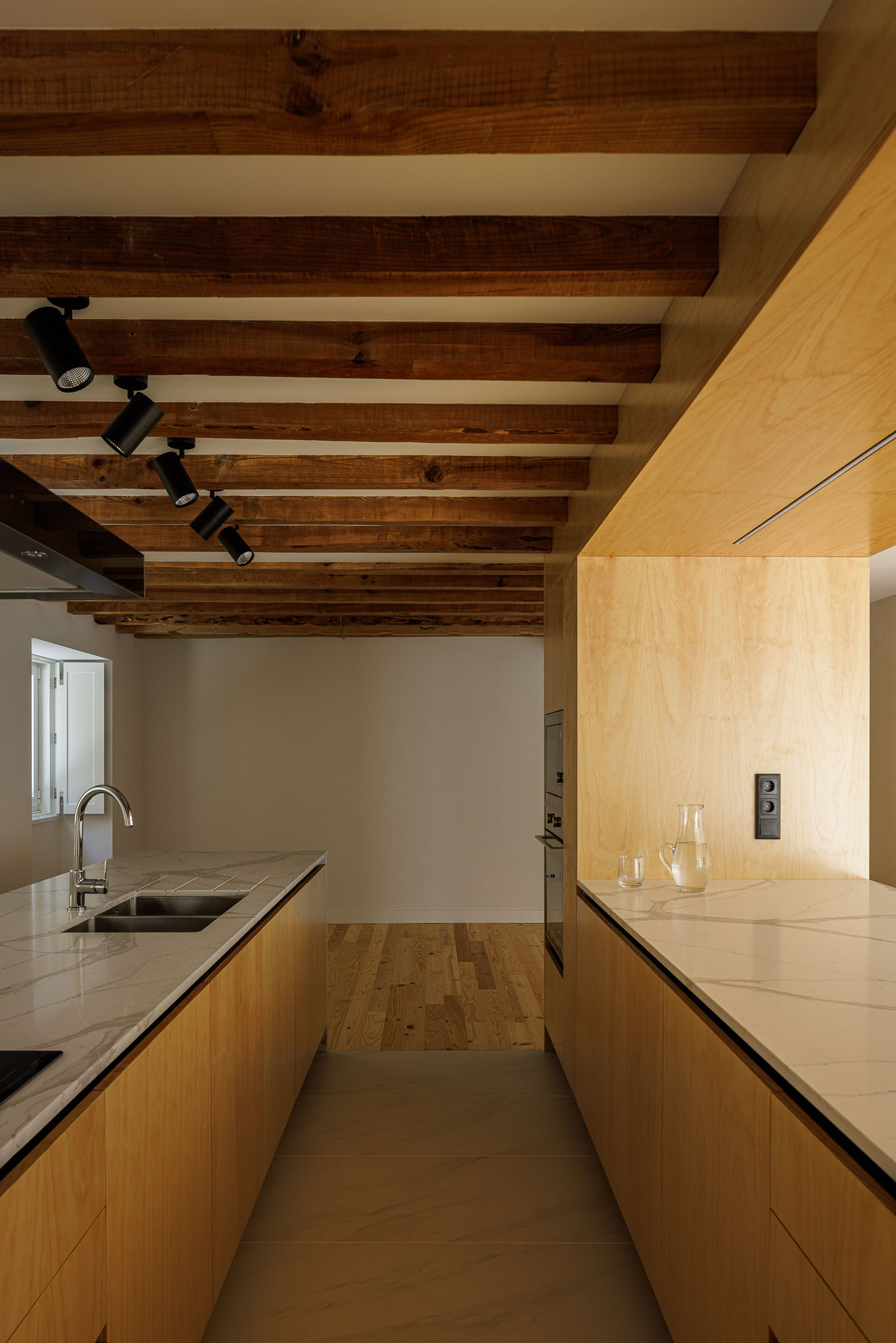 Cozinha: Detalhe da ilha da cozinha com lavatório, armários em madeira clara e teto com vigas de madeira aparente. — Casa dos anos 40 arquitetura Frari em Ílhavo