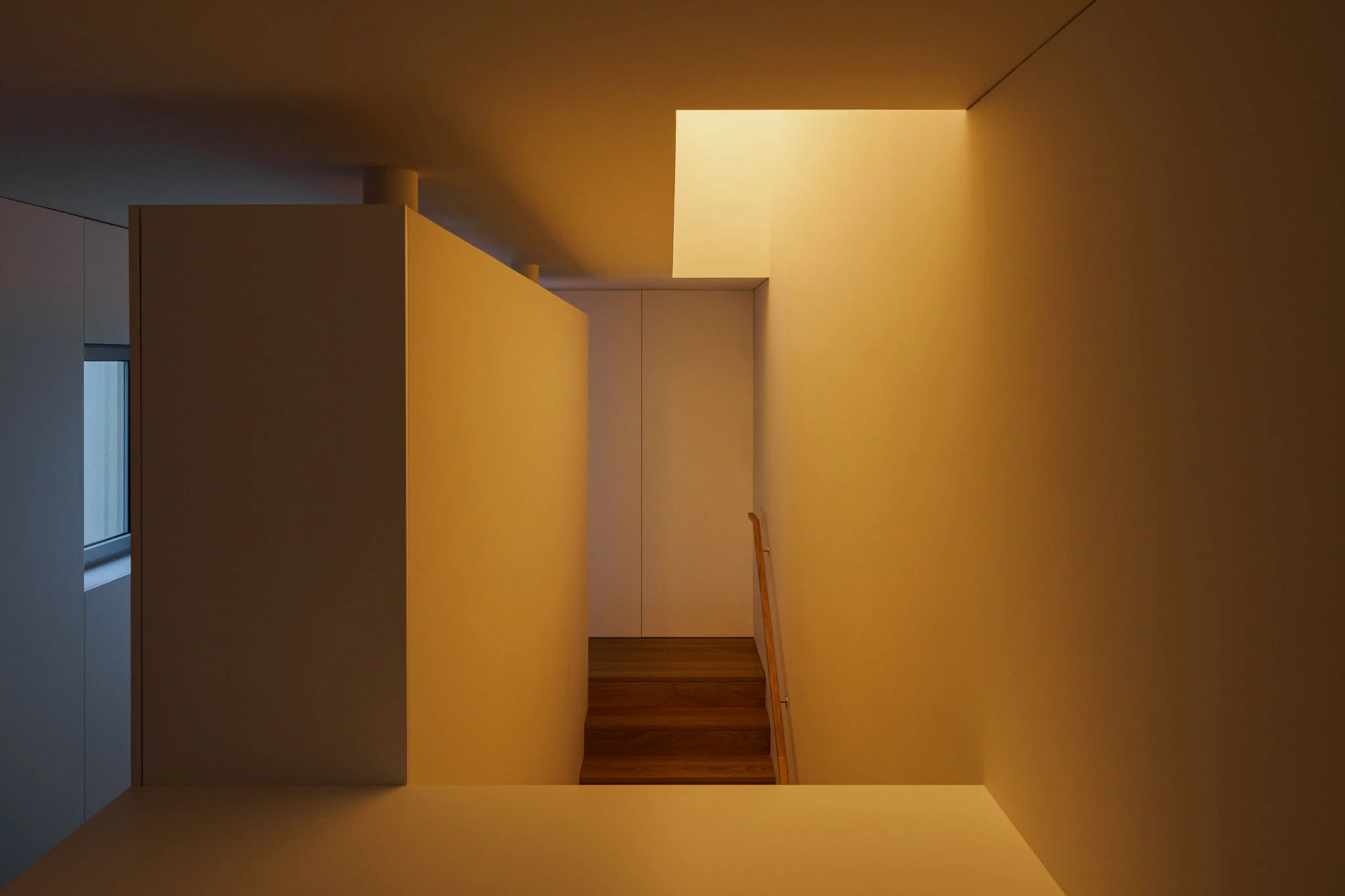Espaço interior com paredes brancas, iluminação indireta e escada ao fundo. — Casa em Santa Marinha arquitetura Helder da Rocha Arquitectos em Lousada