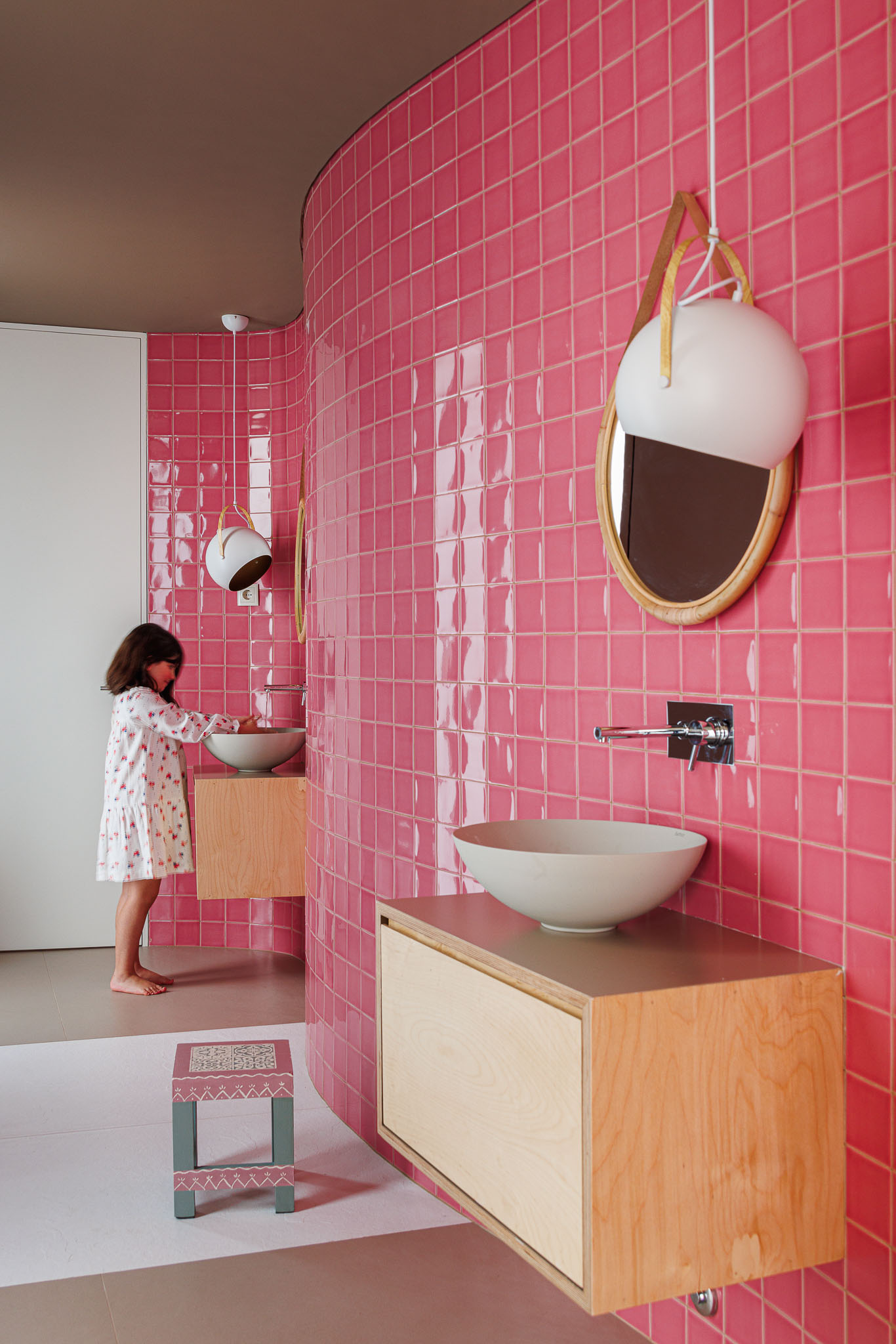 Casa de banho infantil: Azulejos rosa, lavatórios circulares, espelhos com moldura em vime e pavimento rosa e branco. — Casa Pátios de Pétalas arquitetura Sandra Micaela Casinha Atelier em Gondomar