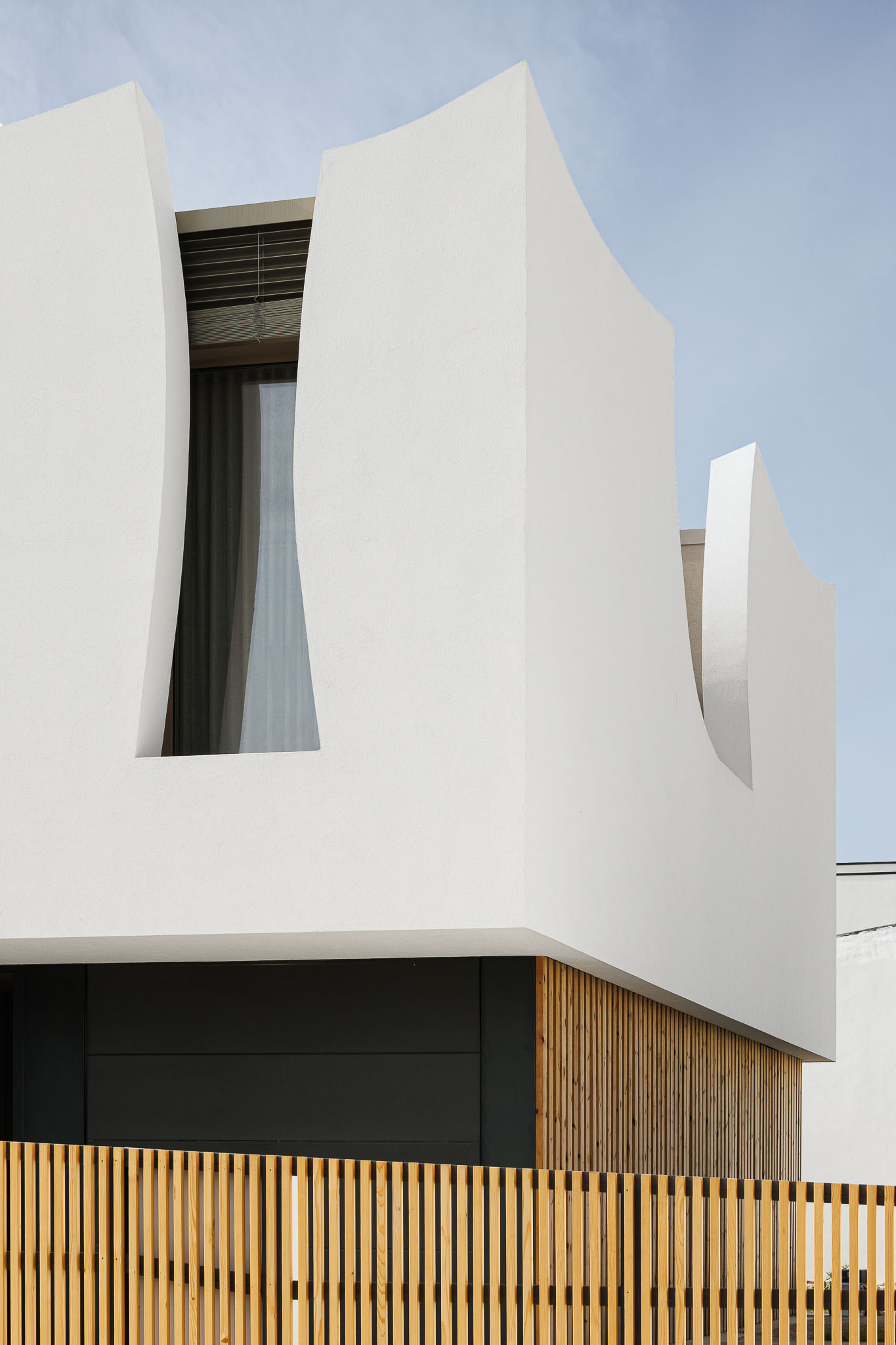 Exterior: Fachada branca com detalhes curvos e revestimento em madeira vertical. — Casa Pátios de Pétalas arquitetura Sandra Micaela Casinha Atelier em Gondomar