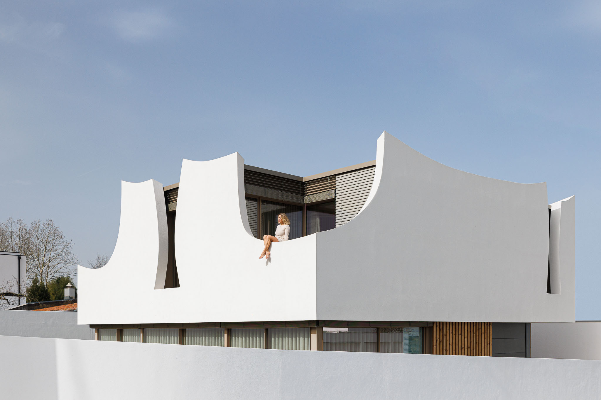 Exterior: Vista superior da casa com detalhes curvos e varanda. — Casa Pátios de Pétalas arquitetura Sandra Micaela Casinha Atelier em Gondomar