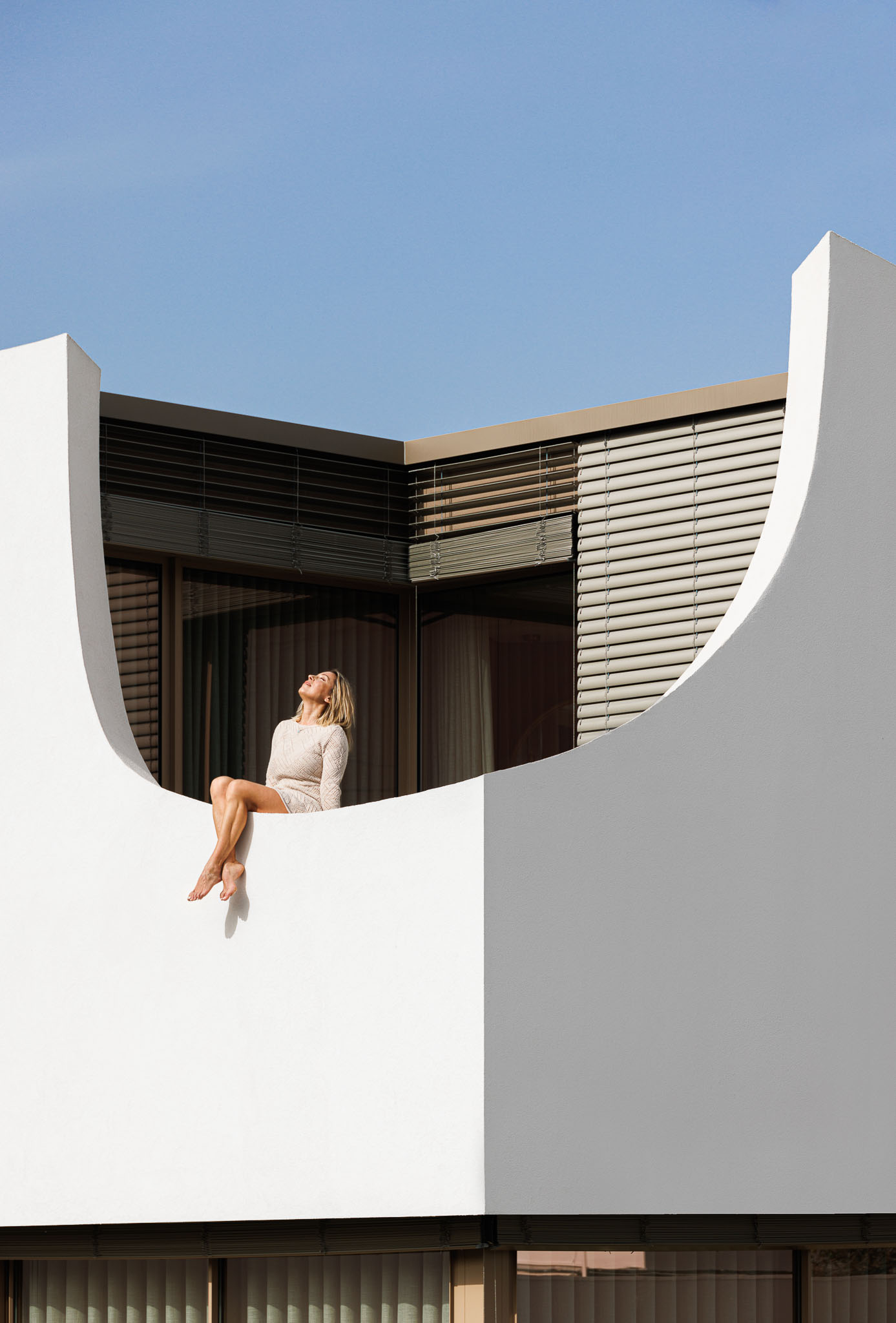 Exterior: Detalhe da varanda curva branca com ripas horizontais. — Casa Pátios de Pétalas arquitetura Sandra Micaela Casinha Atelier em Gondomar