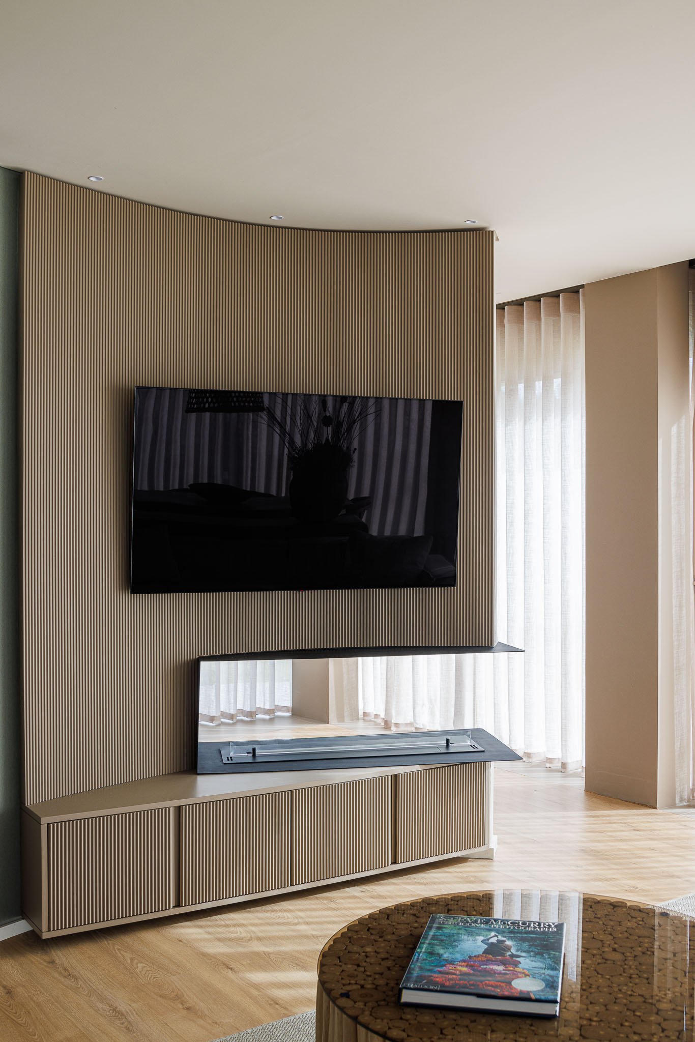 Sala de estar: Móvel de televisão em madeira com lamelas verticais e pavimento em madeira. — Casa Pátios de Pétalas arquitetura Sandra Micaela Casinha Atelier em Gondomar