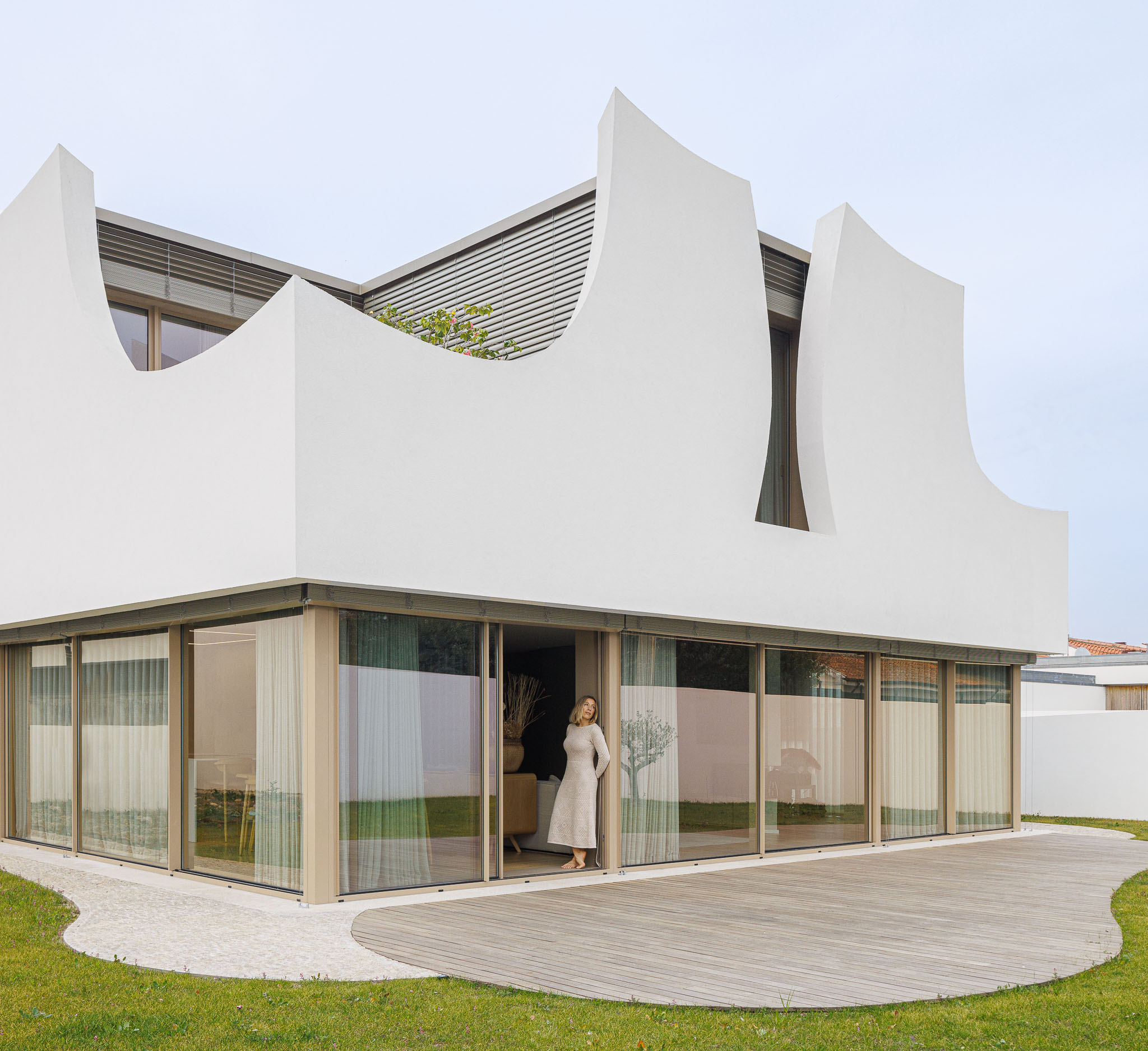 Exterior: Fachada da casa com janelas amplas e deck de madeira. — Casa Pátios de Pétalas arquitetura Sandra Micaela Casinha Atelier em Gondomar