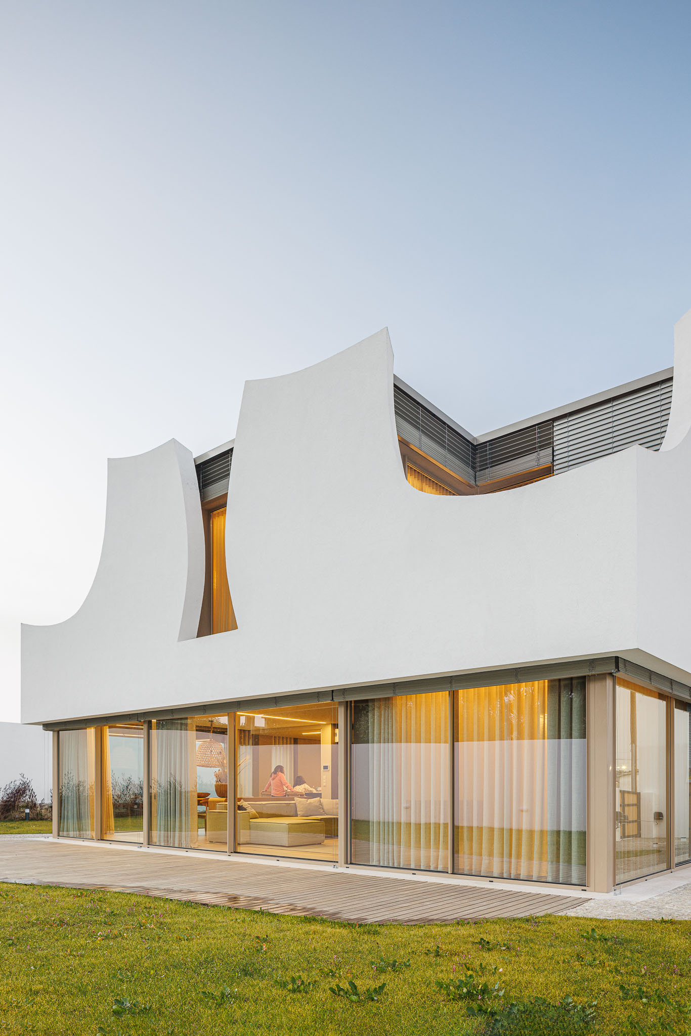 Exterior: Fachada da casa com janelas amplas e deck de madeira. — Casa Pátios de Pétalas arquitetura Sandra Micaela Casinha Atelier em Gondomar