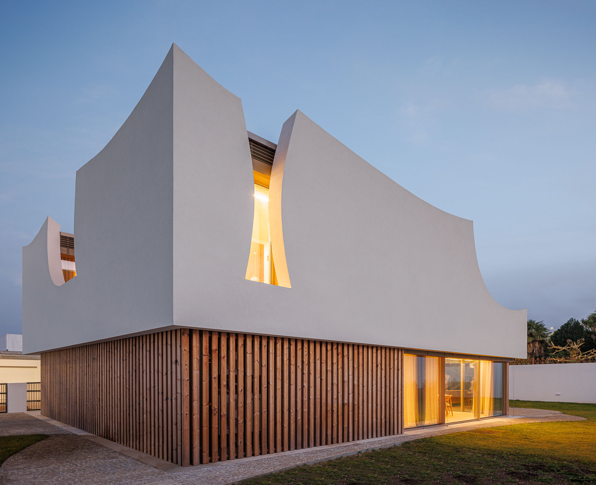 Exterior: Fachada da casa com detalhes curvos e revestimento em madeira. — Casa Pátios de Pétalas arquitetura Sandra Micaela Casinha Atelier em Gondomar