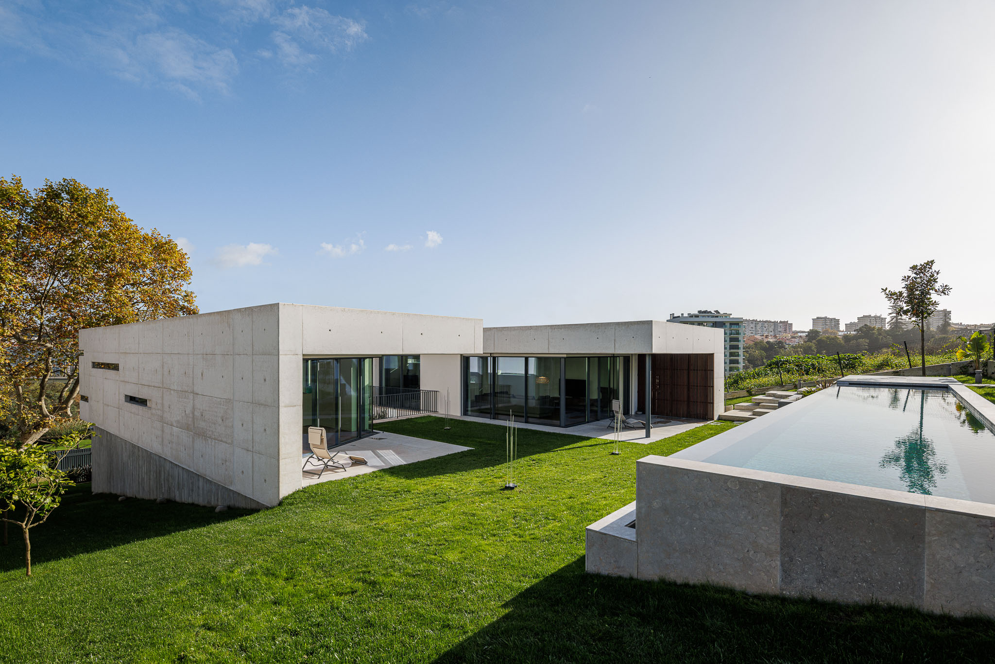 Exterior: Moradia moderna com piscina, jardim relvado e vista para a paisagem urbana. — CONCRETE 11 arquitetura Cage Atelier em Lisboa