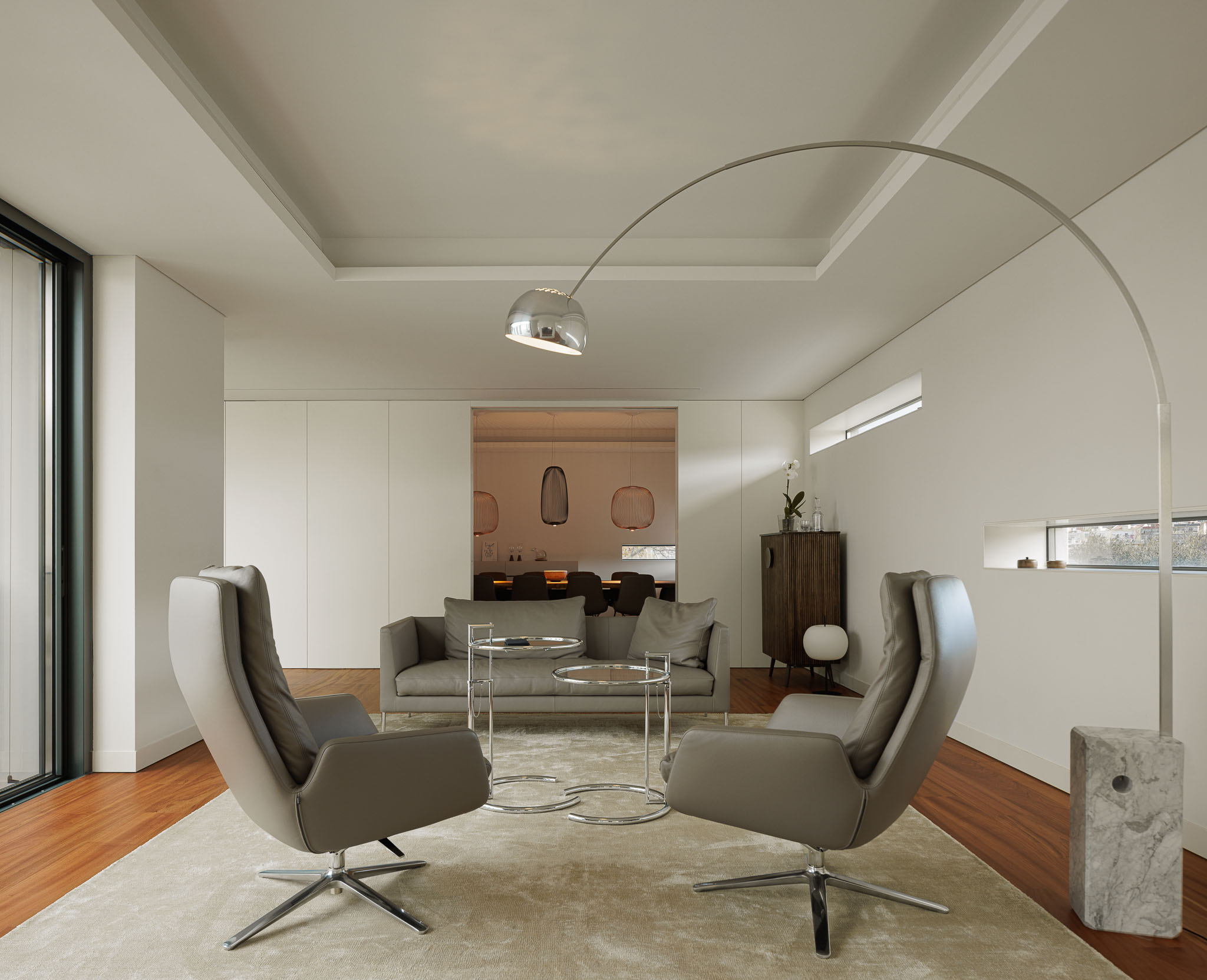 Sala de estar: Sofá cinzento, cadeirões giratórios, mesa de centro e candeeiro de pé em arco. Pavimento em madeira. — CONCRETE 11 arquitetura Cage Atelier em Lisboa