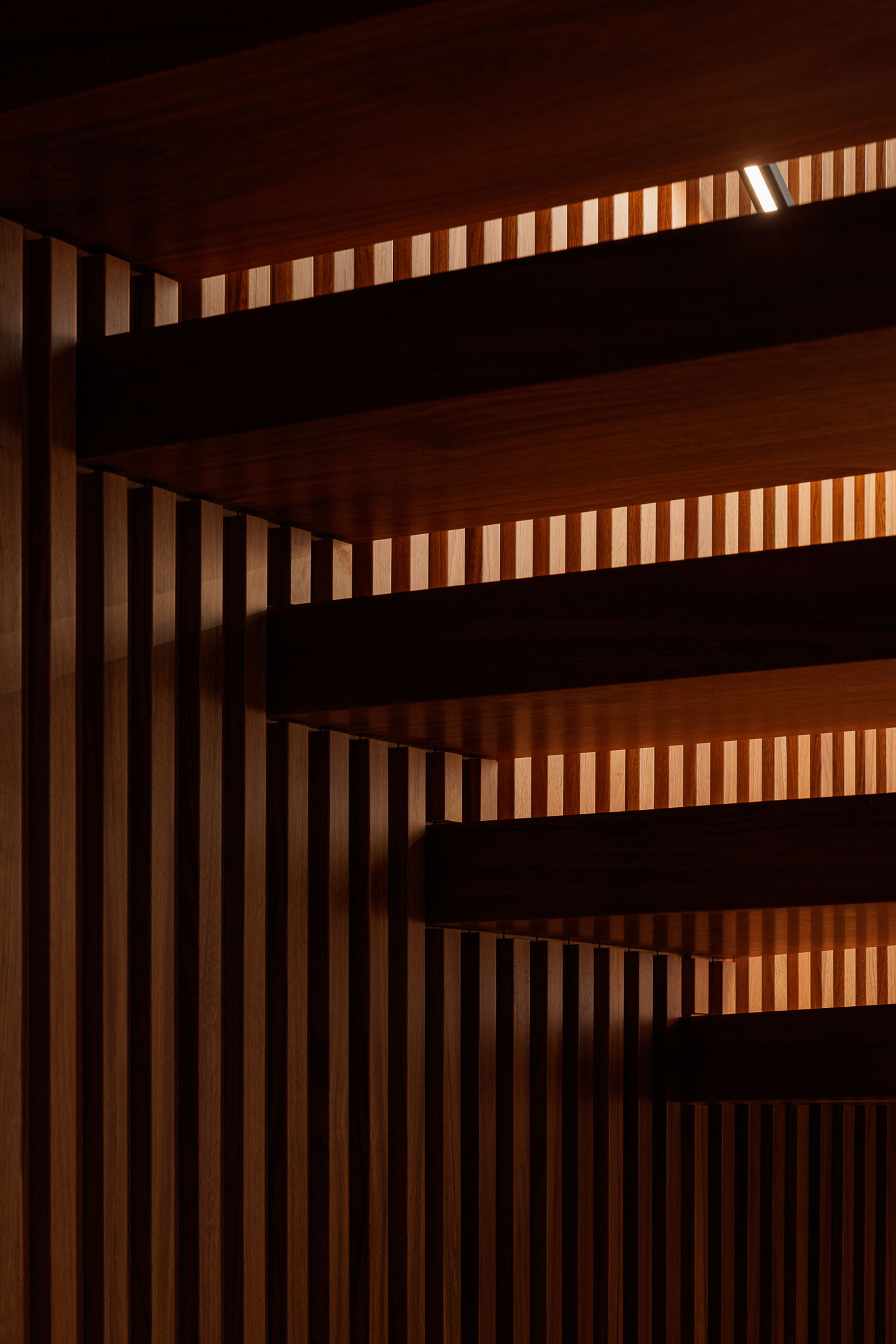 Escada: Detalhe dos degraus de madeira com iluminação indireta e painéis verticais de madeira. — CONCRETE 11 arquitetura Cage Atelier em Lisboa