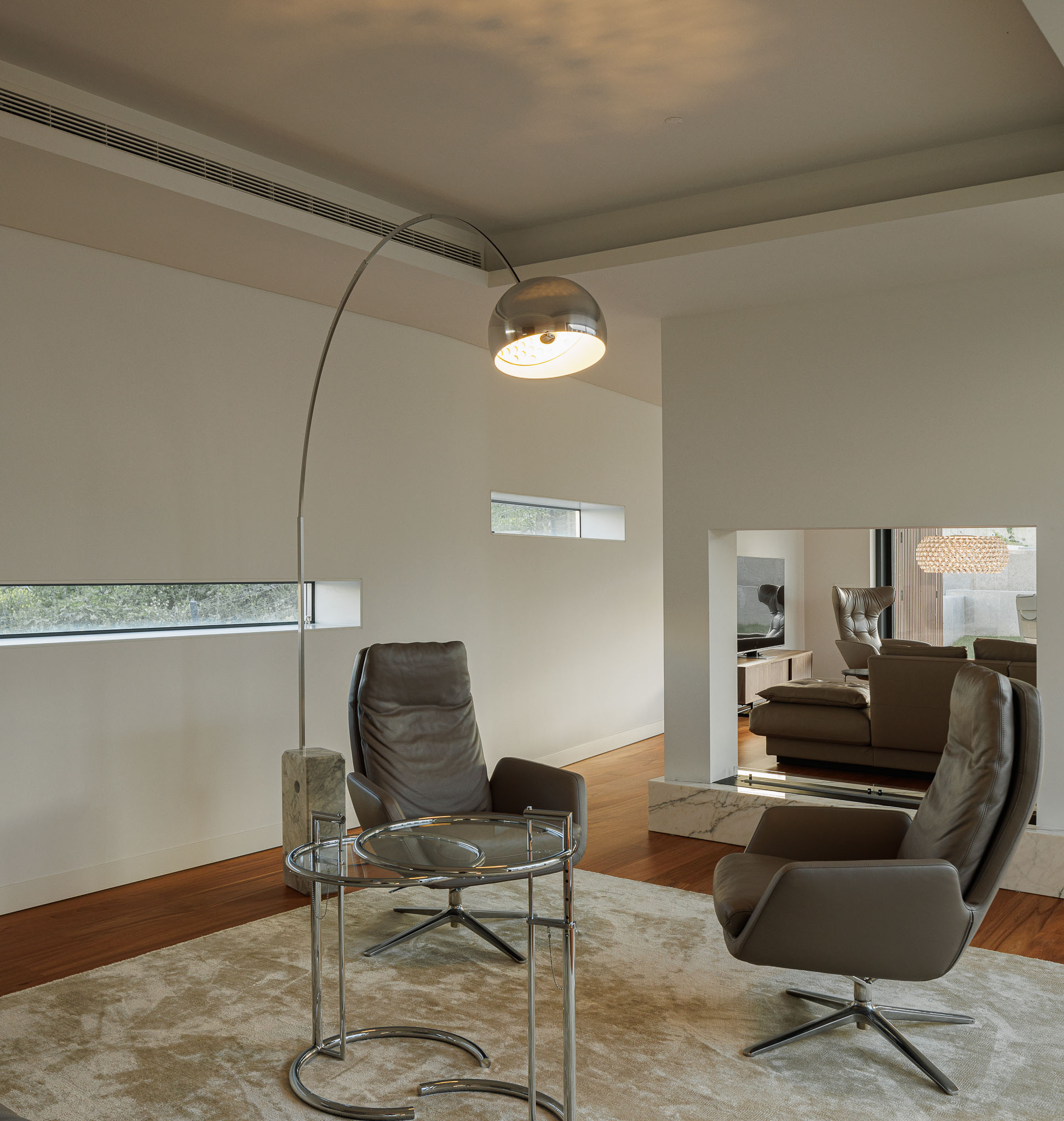Sala de estar: Cadeirões giratórios, mesa de centro, candeeiro de pé em arco e pavimento em madeira. — CONCRETE 11 arquitetura Cage Atelier em Lisboa