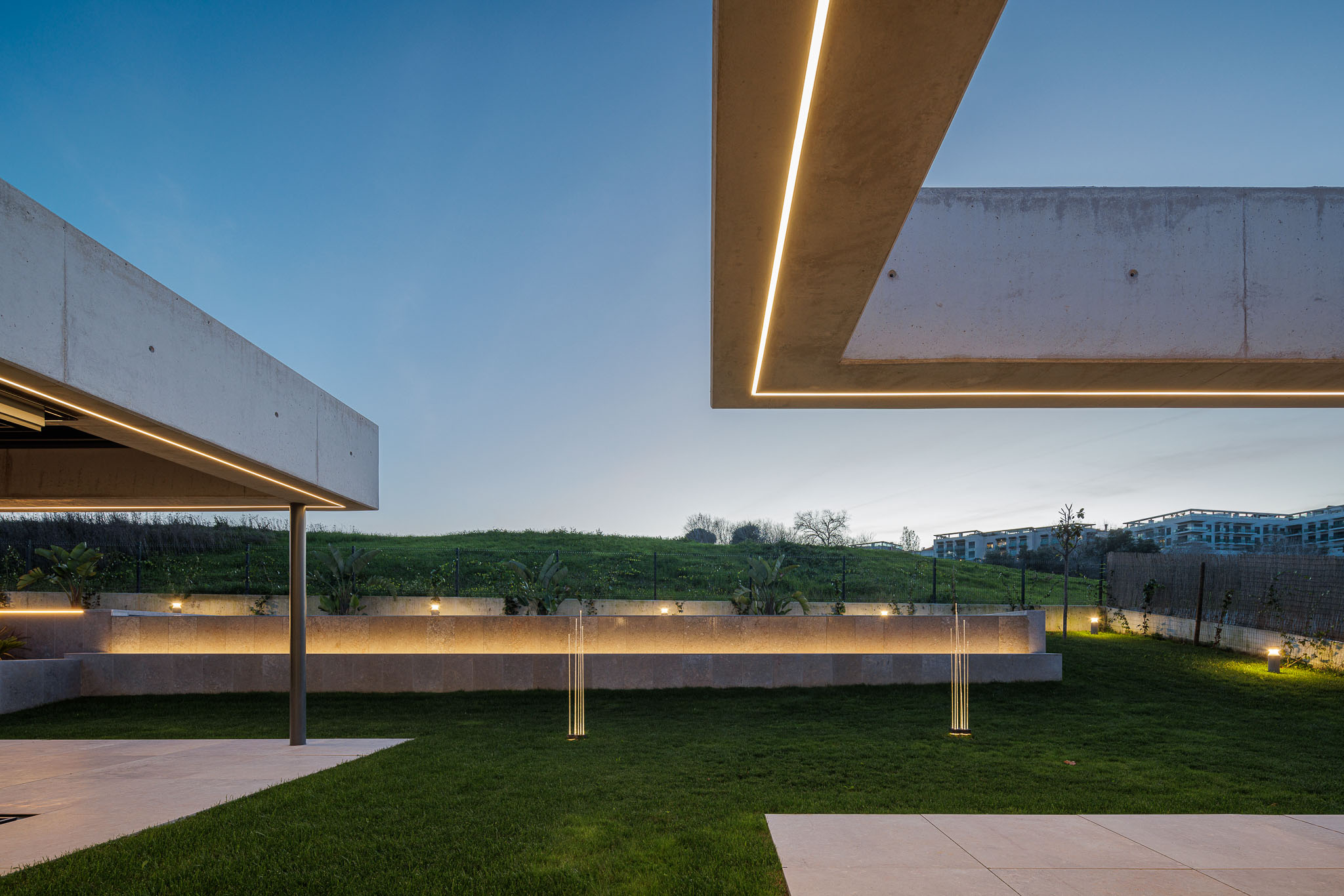 Exterior: Iluminação exterior com candeeiros embutidos no muro e projetores no jardim relvado. — CONCRETE 11 arquitetura Cage Atelier em Lisboa