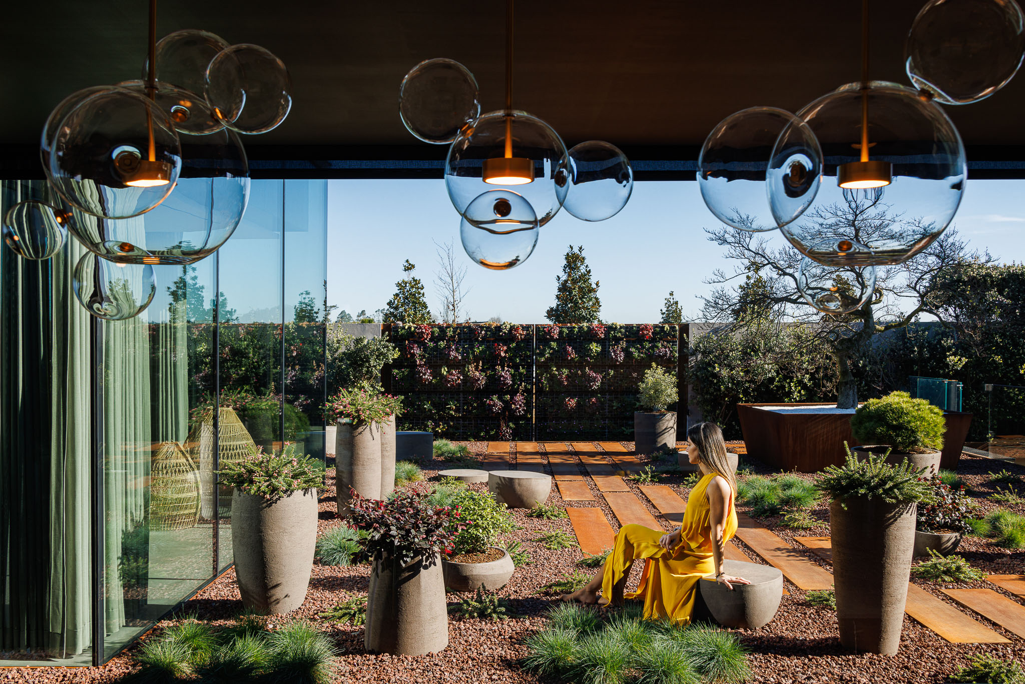 Jardim: Espaço exterior com vegetação densa, caminhos de corten, candeeiros suspensos de vidro e banheira de imersão. — Casa de Lavra arquitetura Ricardo Azevedo Arquitecto em Matosinhos