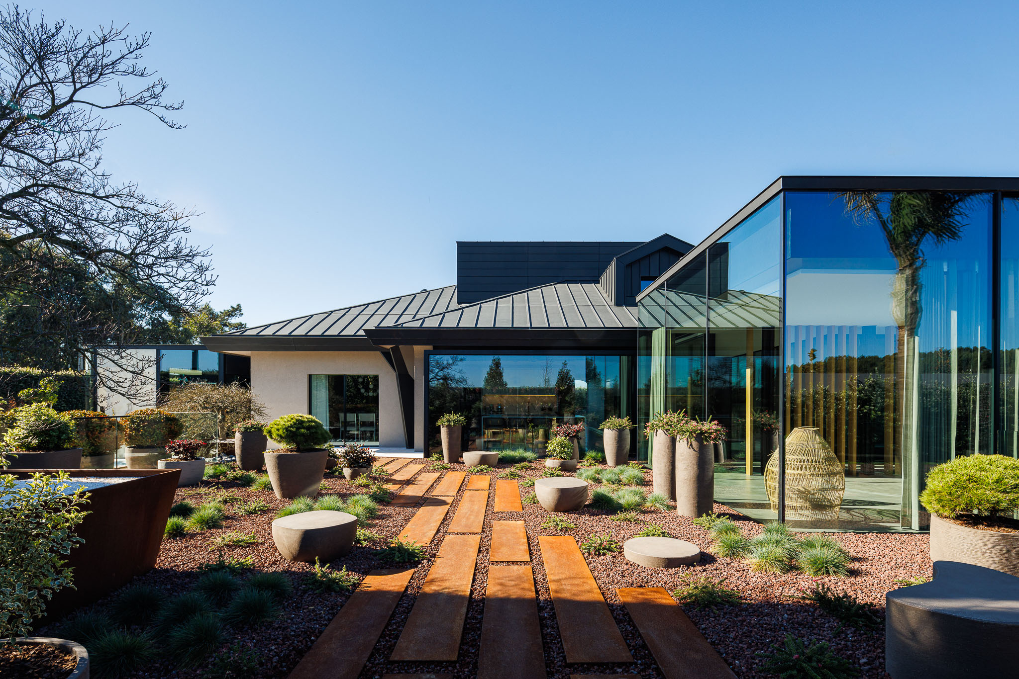 Exterior: Fachada envidraçada e revestimento em zinco, com jardim paisagístico e caminhos de corten. — Casa de Lavra arquitetura Ricardo Azevedo Arquitecto em Matosinhos