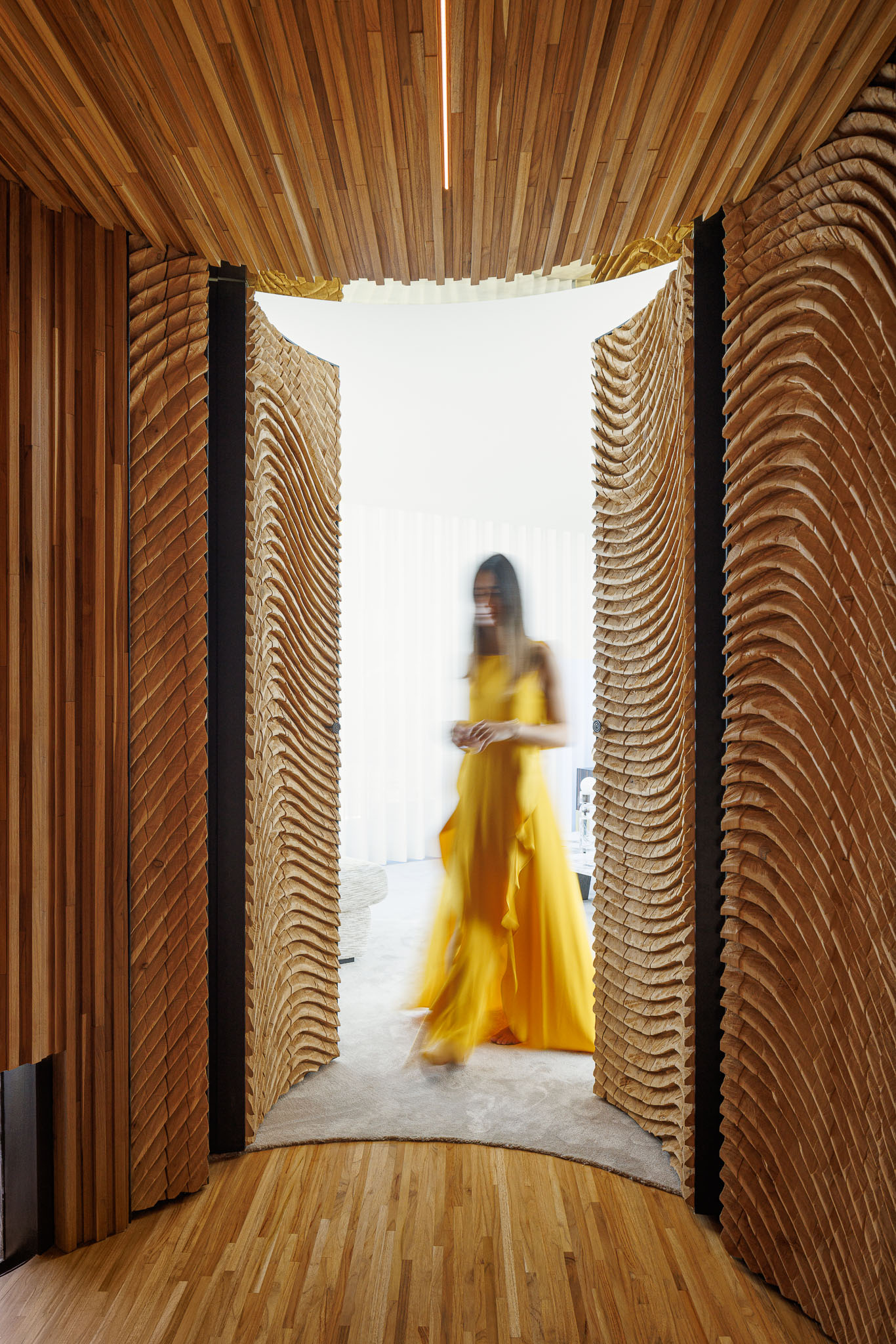 Corredor: Portas em madeira com padrão ondulado, pavimento e teto em madeira, com vista para a sala de estar. — Casa de Lavra arquitetura Ricardo Azevedo Arquitecto em Matosinhos