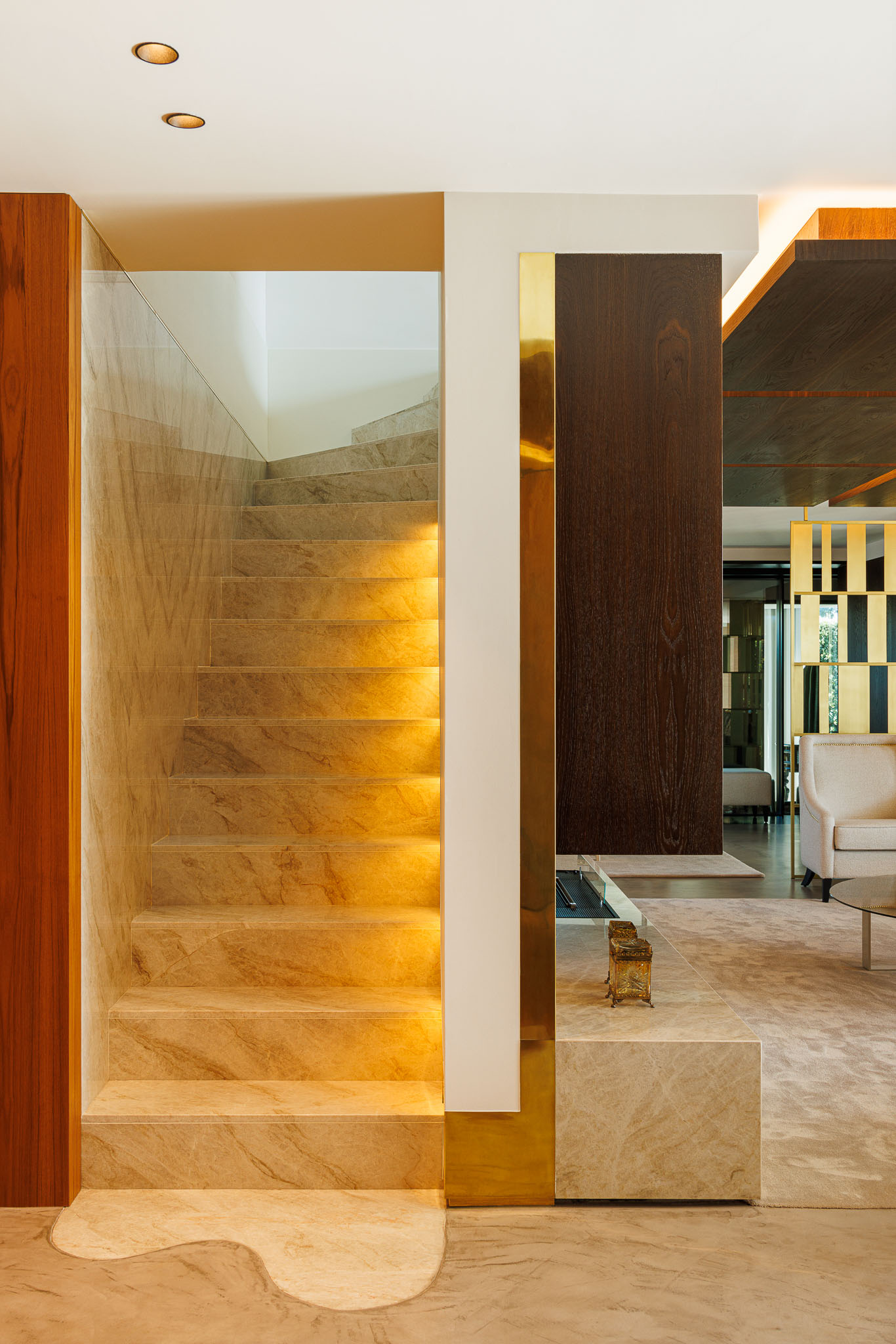 Escada: Degraus em mármore iluminados, com corrimão em vidro e detalhes em madeira e dourado. — Casa de Lavra arquitetura Ricardo Azevedo Arquitecto em Matosinhos