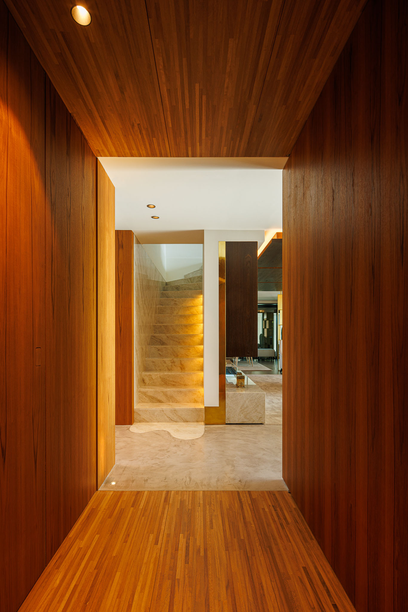 Corredor: Revestimento em madeira, pavimento em madeira e vista para a escada em mármore iluminada. — Casa de Lavra arquitetura Ricardo Azevedo Arquitecto em Matosinhos