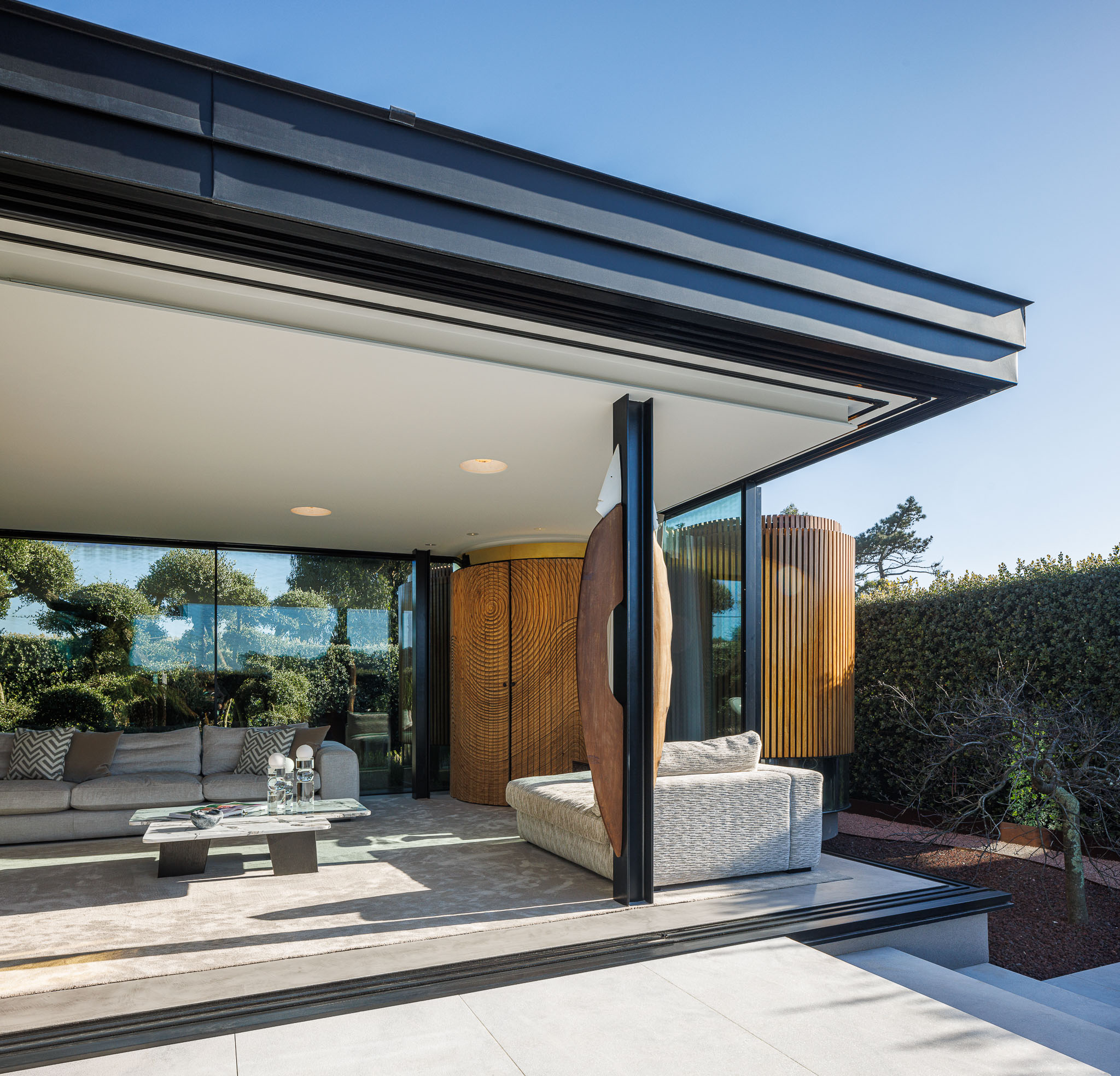 Sala de Estar: Espaço amplo com sofás em tons neutros, divisória em madeira e janelas panorâmicas. — Casa de Lavra arquitetura Ricardo Azevedo Arquitecto em Matosinhos