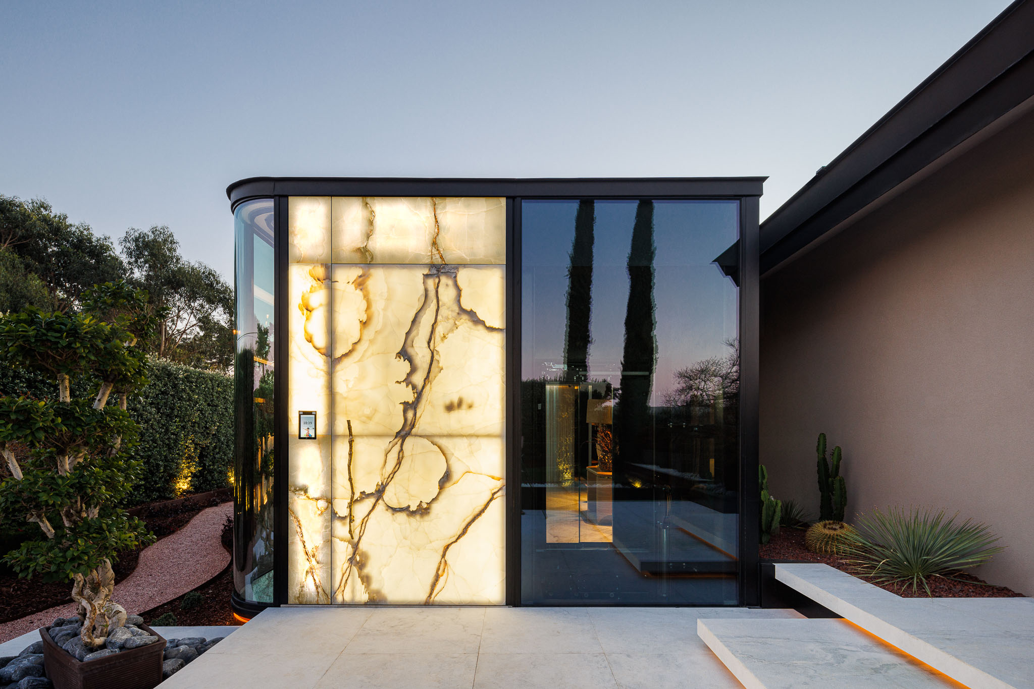 Entrada: Fachada em ónix translúcido iluminado, com detalhes em vidro e metal preto. — Casa de Lavra arquitetura Ricardo Azevedo Arquitecto em Matosinhos