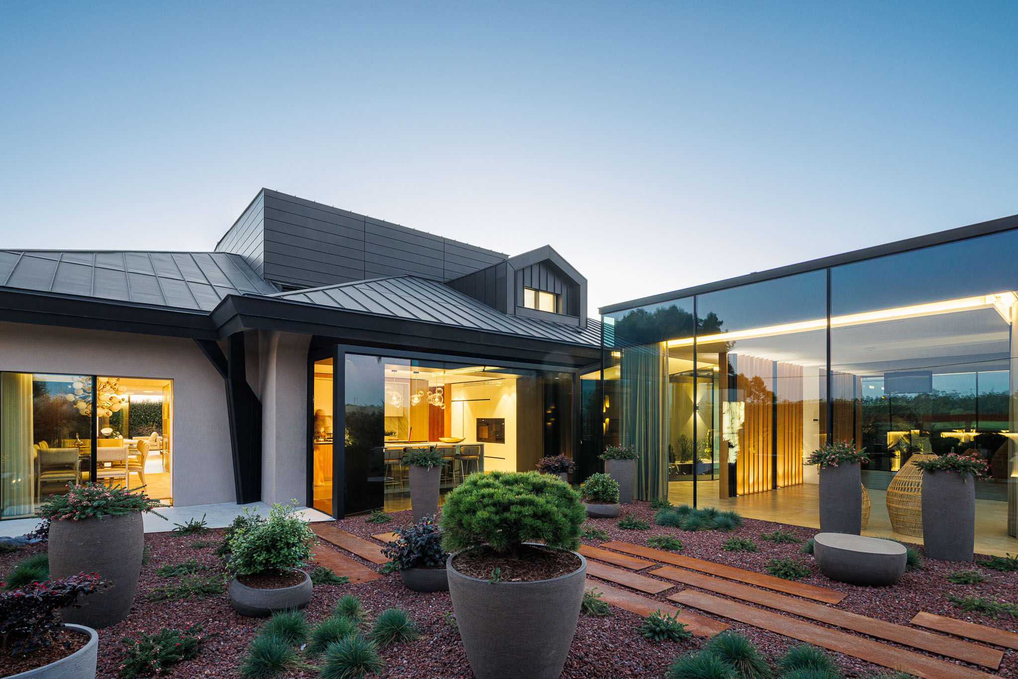 Exterior: Vista geral da casa com jardim paisagístico, fachadas envidraçadas e iluminação noturna. — Casa de Lavra arquitetura Ricardo Azevedo Arquitecto em Matosinhos