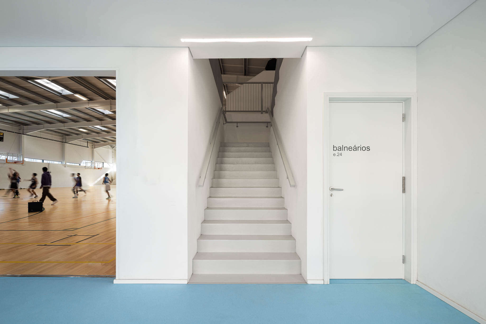 Hall: Corredor com pavimento azul, porta para os balneários e acesso ao pavilhão. — Pavilhão Desportivo da Escola Secundária Eça de Queirós arquitetura Oval em Póvoa de Varzim