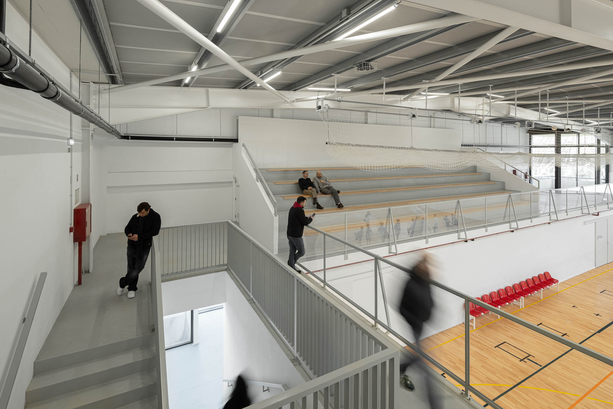Escadas: Escadas com estrutura metálica e paredes brancas, iluminação linear no teto. — Pavilhão Desportivo da Escola Secundária Eça de Queirós arquitetura Oval em Póvoa de Varzim