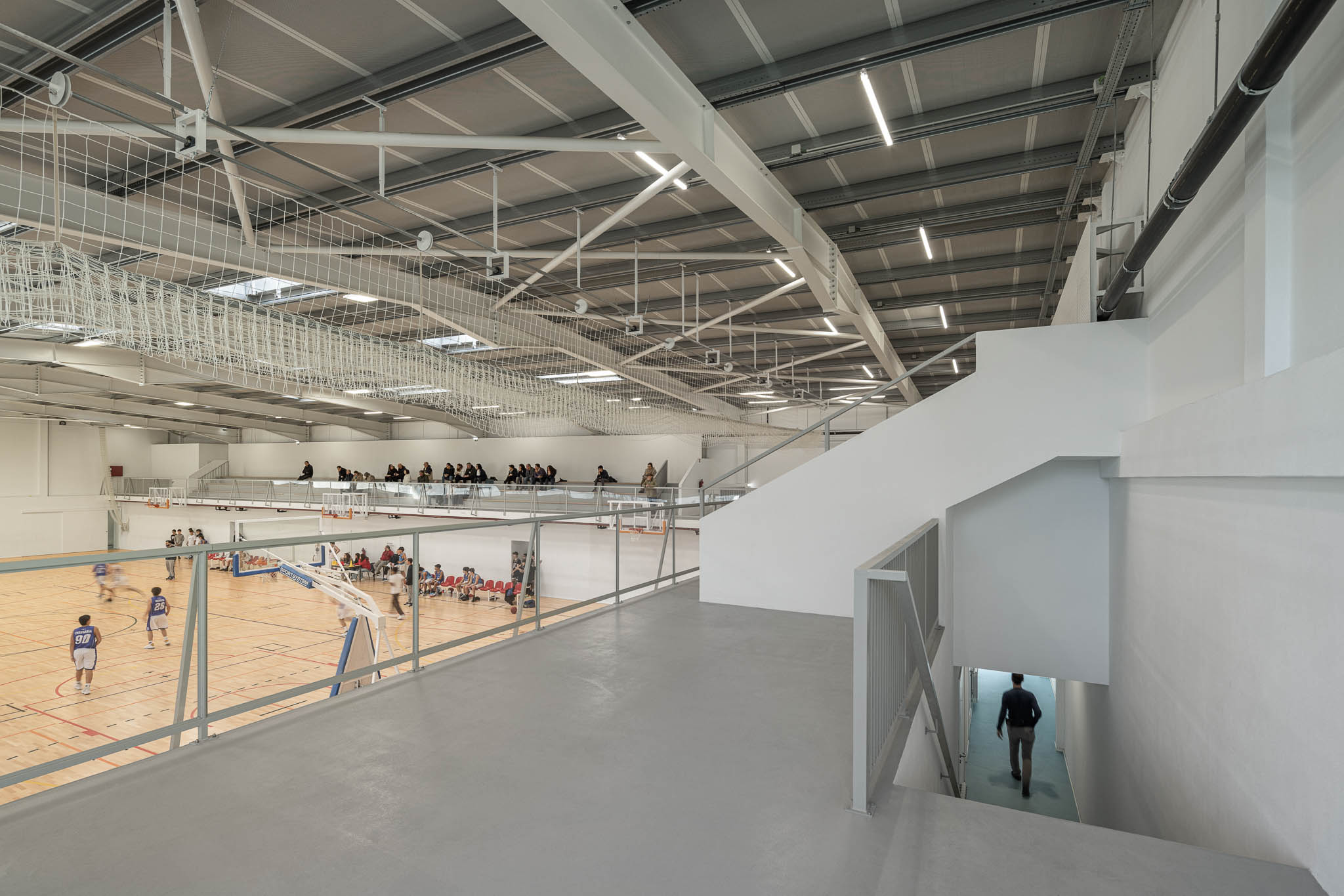 Bancada: Vista da bancada superior para as escadas e o pavilhão, pavimento cinzento. — Pavilhão Desportivo da Escola Secundária Eça de Queirós arquitetura Oval em Póvoa de Varzim