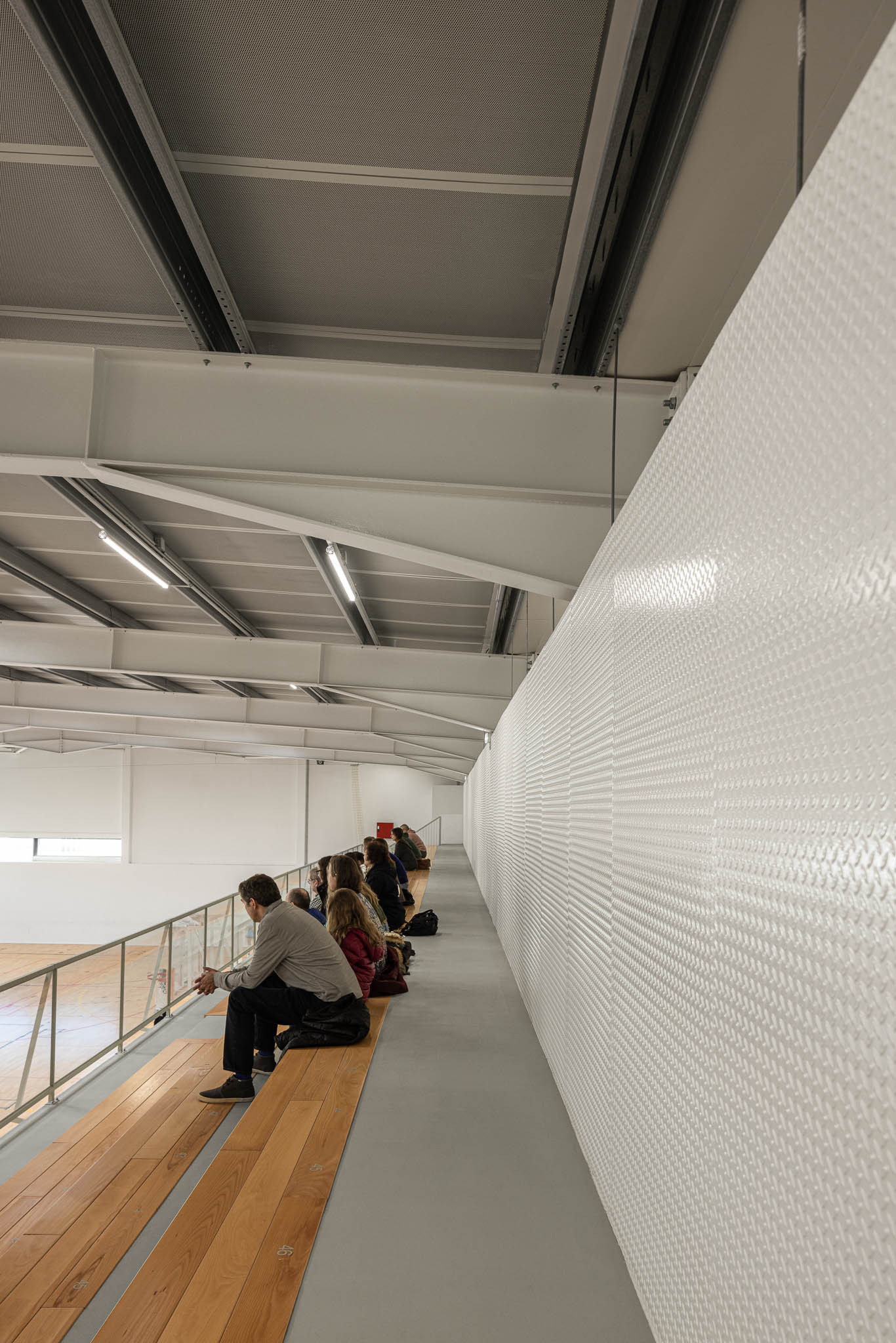 Pavilhão: Campo de basquetebol com tabelas e jogadores, estrutura metálica no teto. — Pavilhão Desportivo da Escola Secundária Eça de Queirós arquitetura Oval em Póvoa de Varzim