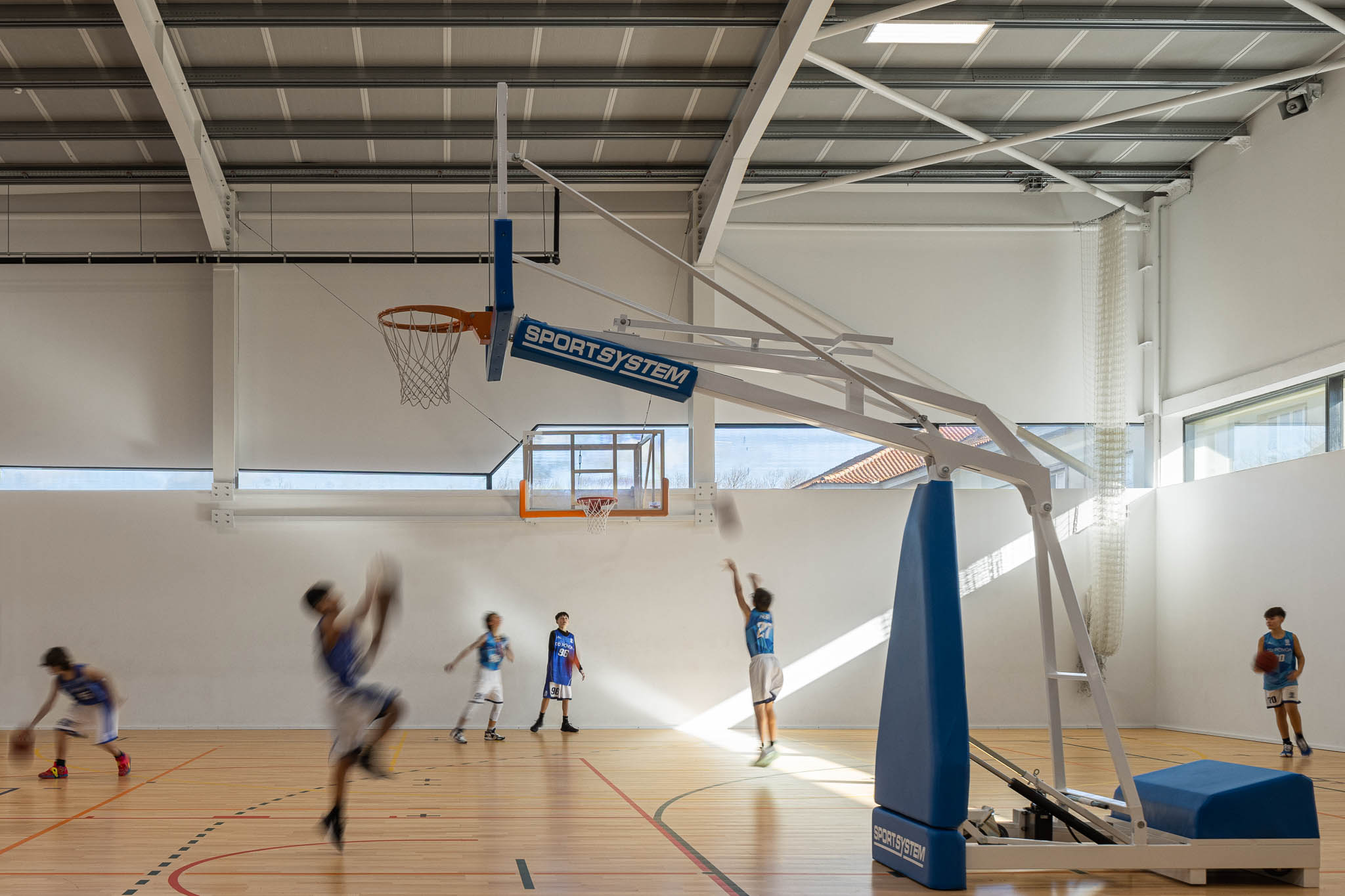 Pavilhão: Vista geral do pavilhão com campo de jogos, bancadas e estrutura metálica no teto. — Pavilhão Desportivo da Escola Secundária Eça de Queirós arquitetura Oval em Póvoa de Varzim