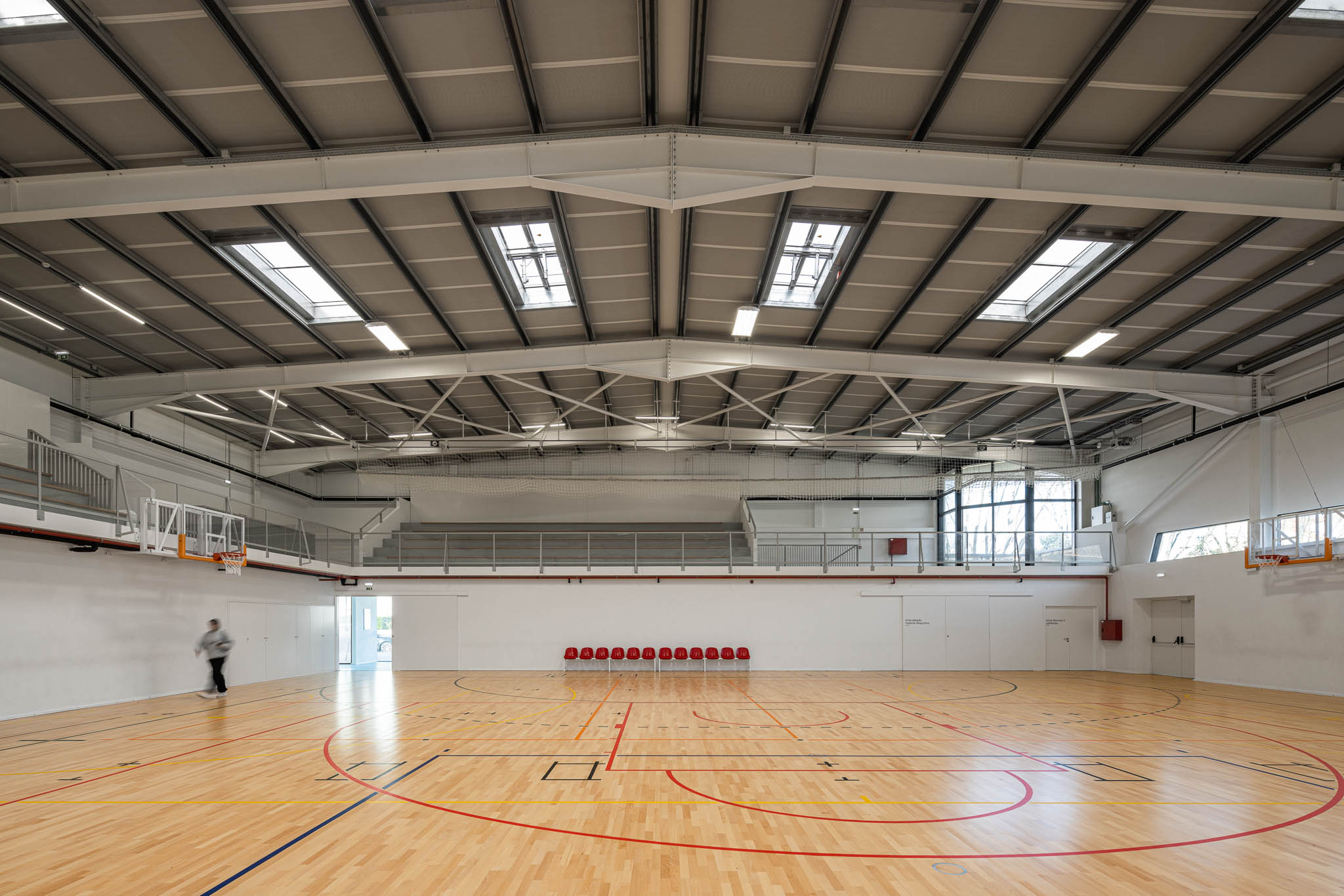 Pavilhão: Campo de voleibol com equipas alinhadas, bancadas e iluminação zenital. — Pavilhão Desportivo da Escola Secundária Eça de Queirós arquitetura Oval em Póvoa de Varzim