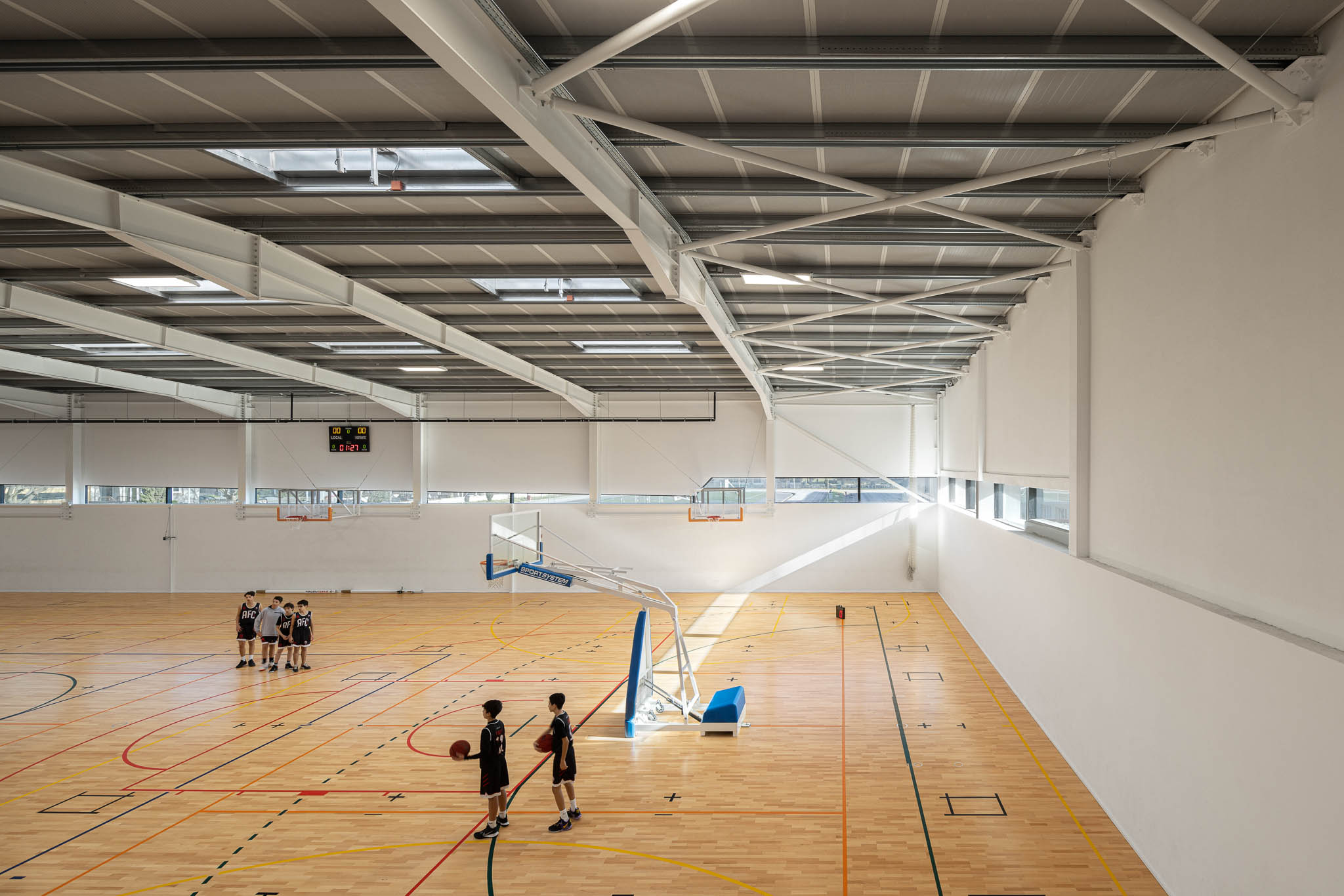 Corredor: Corredor com pavimento azul, acesso ao pavilhão e cadeiras vermelhas. — Pavilhão Desportivo da Escola Secundária Eça de Queirós arquitetura Oval em Póvoa de Varzim
