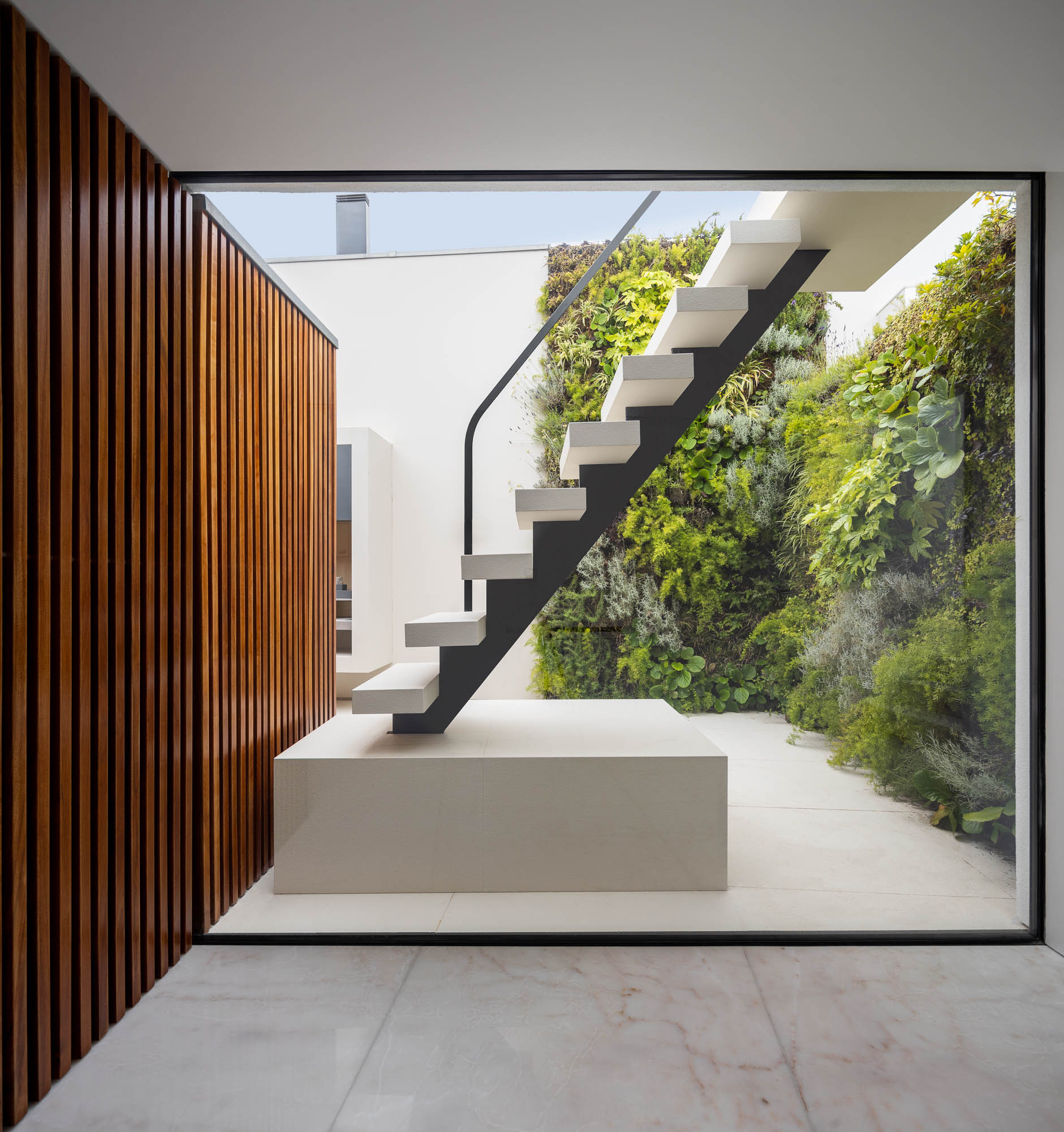 Pátio: Escadas exteriores em betão, parede verde vertical e revestimento em madeira. Integração da natureza no espaço. — Casa Costa Nova arquitetura Espaço Objecto em Ílhavo