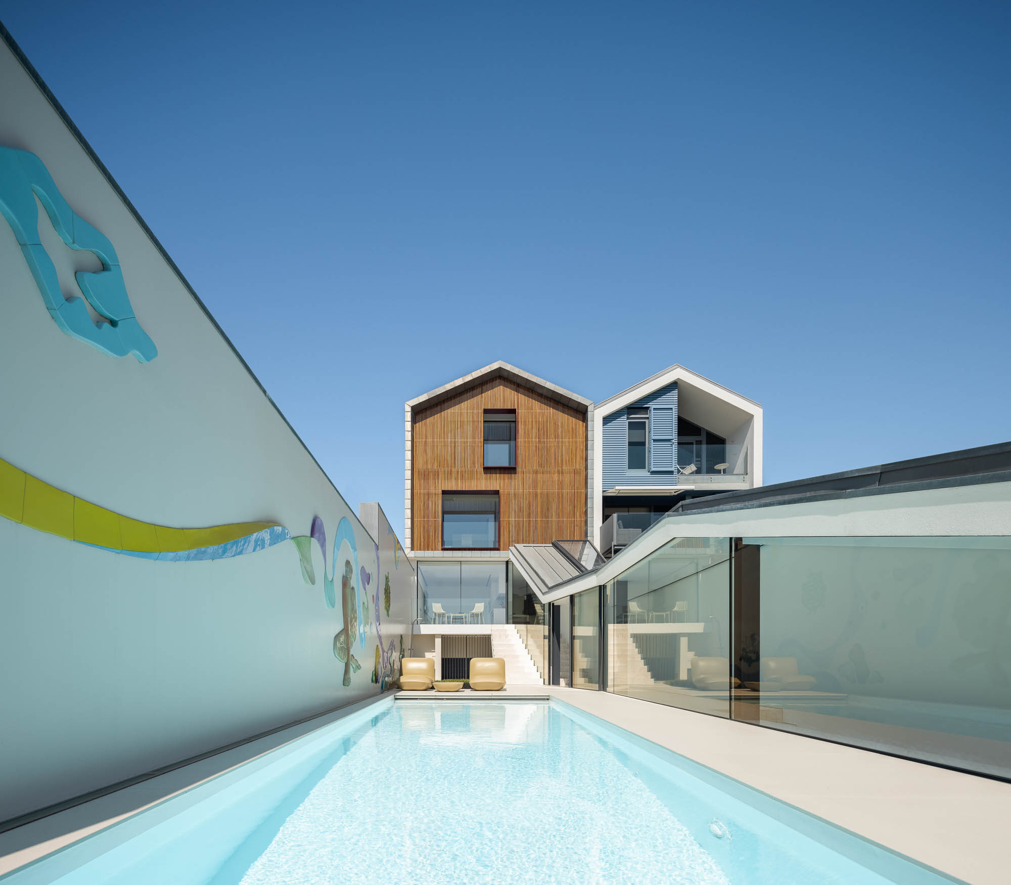 Exterior: Parede com painel cerâmico colorido, espreguiçadeiras e piscina. Detalhes artísticos e ambiente relaxante. — Casa Costa Nova arquitetura Espaço Objecto em Ílhavo