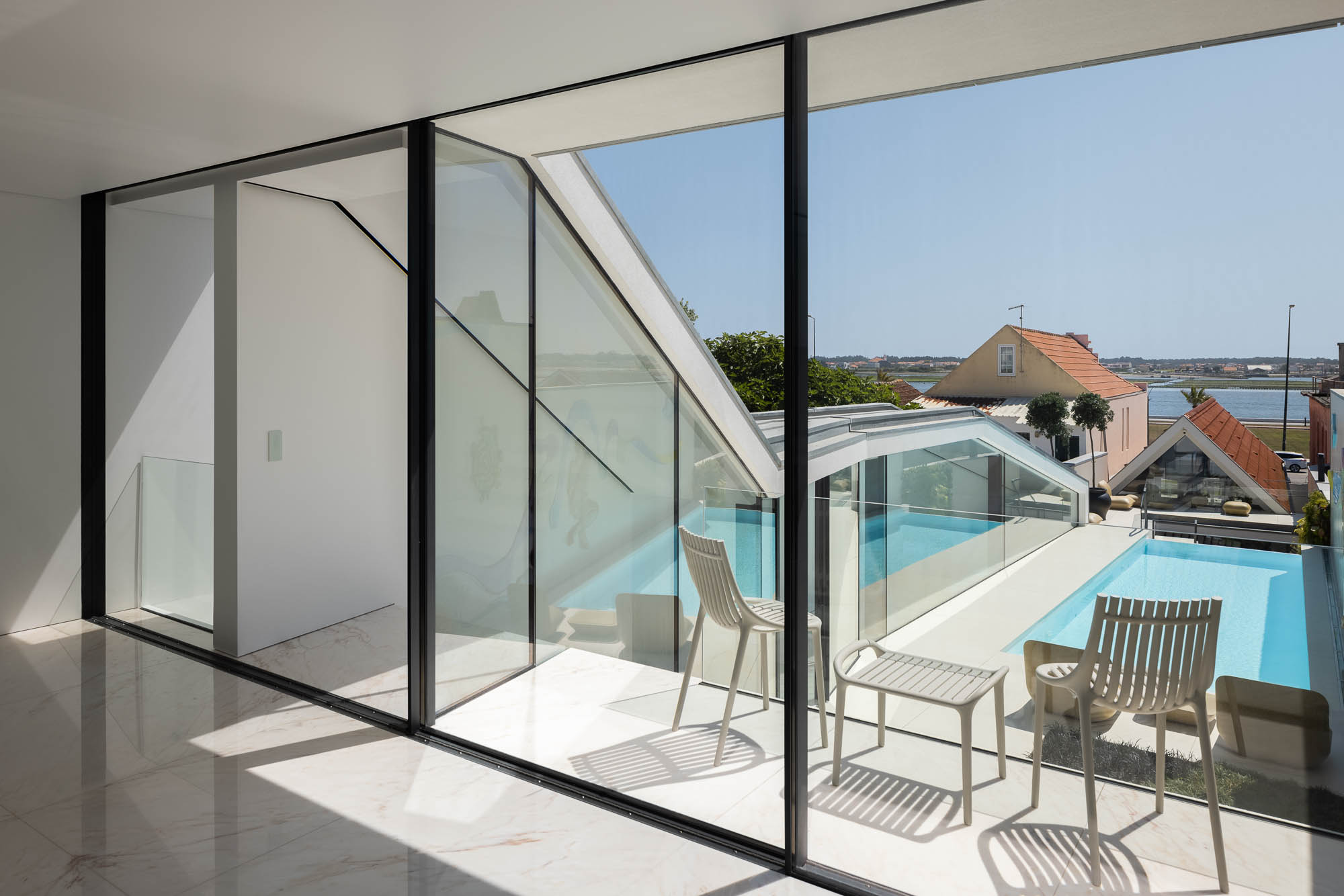 Escadas: Vista vertical das escadas com paredes brancas e janelas com ripas de madeira. Design minimalista e elegante. — Casa Costa Nova arquitetura Espaço Objecto em Ílhavo