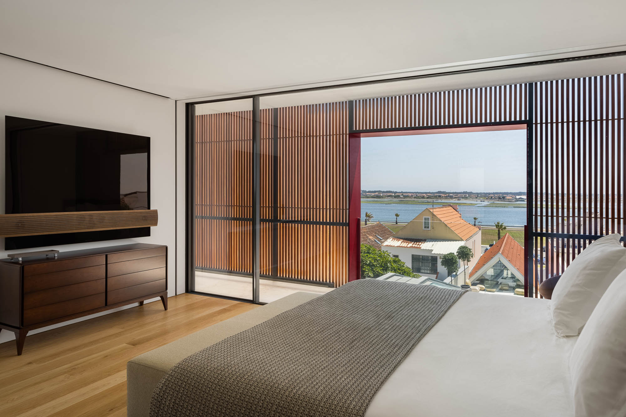 Quarto: Casa de banho integrada com lavatório em mármore, sanita e bidé. Divisão com coluna em mármore e pavimento em madeira. — Casa Costa Nova arquitetura Espaço Objecto em Ílhavo