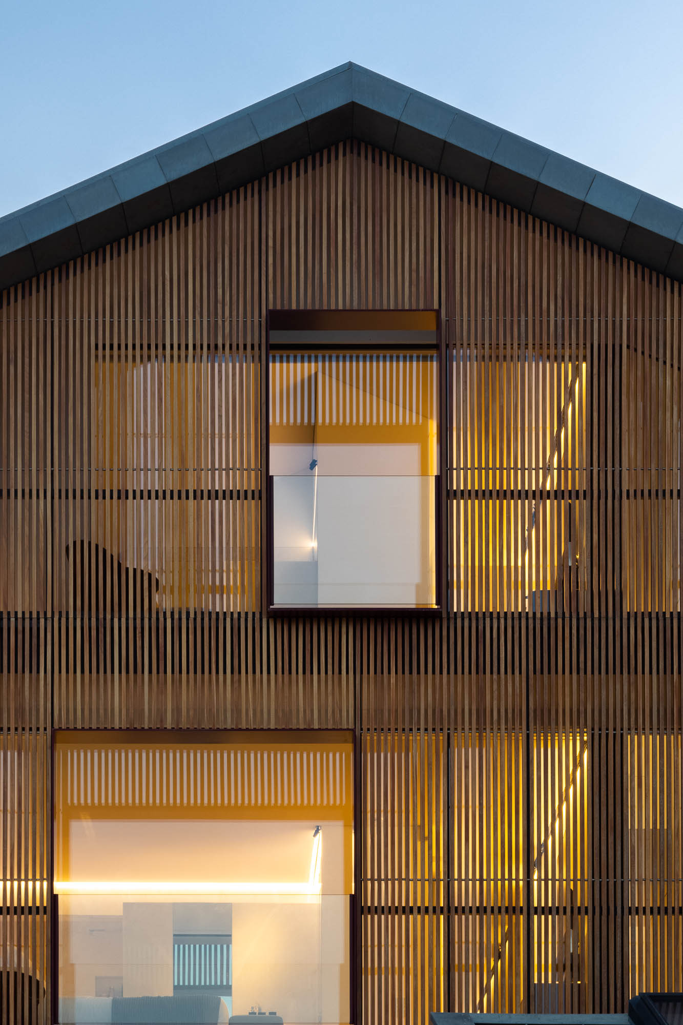Exterior: Pátio com parede verde vertical, lareira e casa com revestimento em madeira. Ambiente acolhedor e moderno. — Casa Costa Nova arquitetura Espaço Objecto em Ílhavo