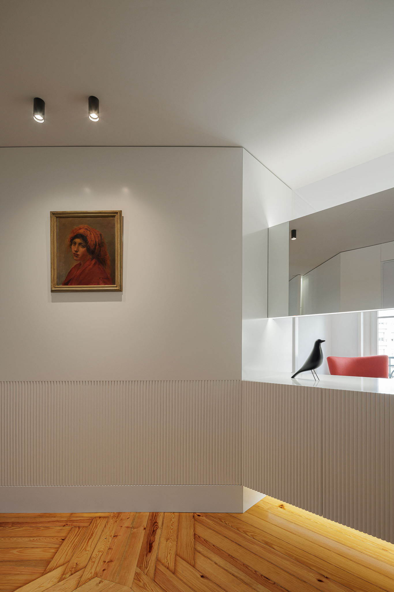 Hall de entrada: Pavimento em madeira, parede com lambris e consola branca com iluminação indireta e decoração. — Apartamento AN arquitetura NMDARQ – Nuno Miguel Dias, Arquitecto em Lisboa