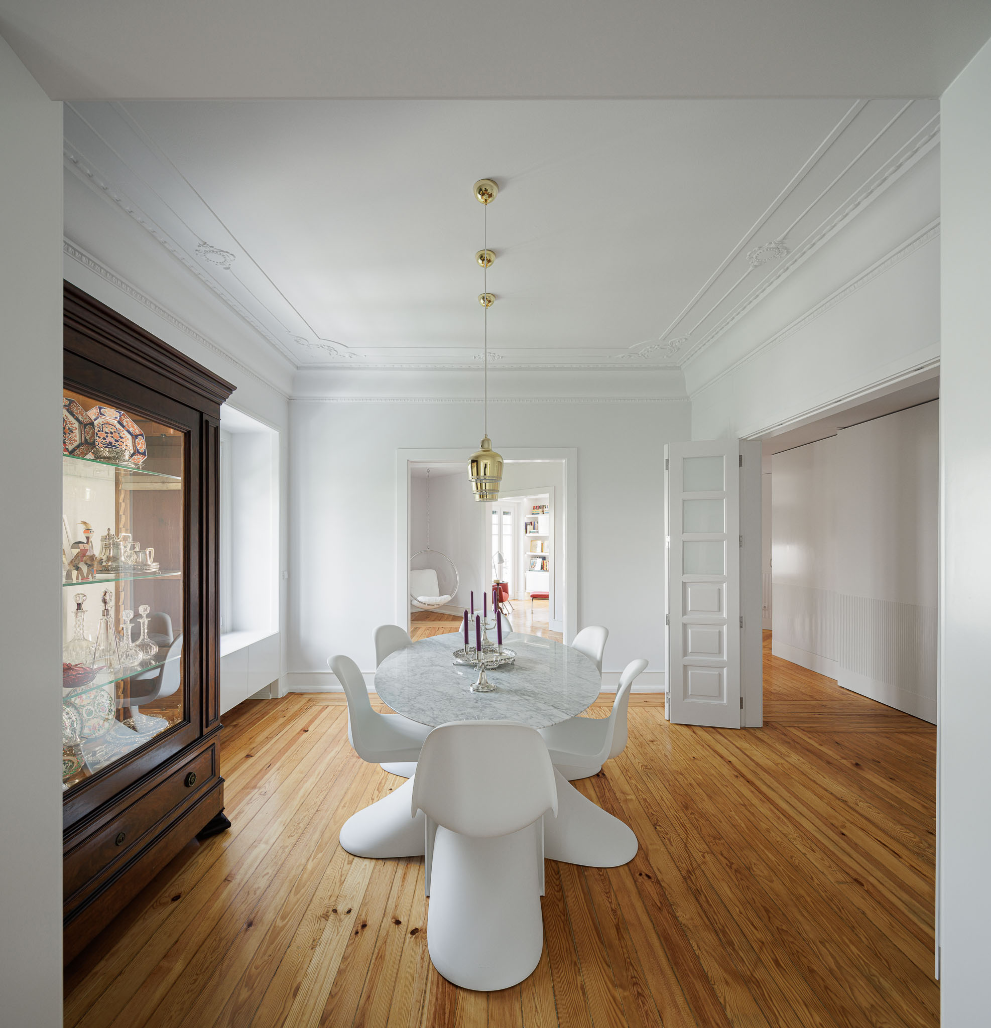 Sala de jantar: Mesa redonda em mármore, cadeiras brancas, candeeiro dourado e aparador clássico em madeira escura. — Apartamento AN arquitetura NMDARQ – Nuno Miguel Dias, Arquitecto em Lisboa