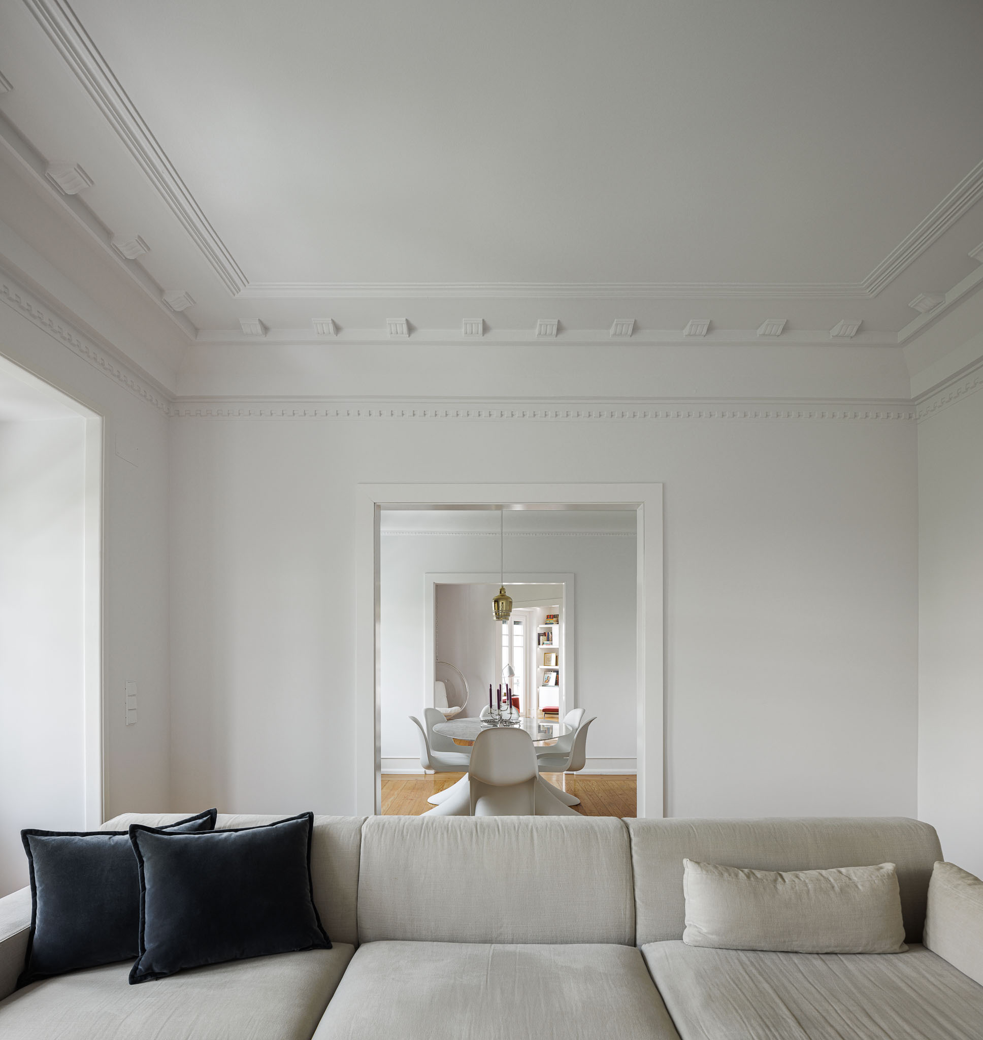 Sala de estar: Sofá cinzento com almofadas escuras, teto trabalhado e vista para a sala de jantar. — Apartamento AN arquitetura NMDARQ – Nuno Miguel Dias, Arquitecto em Lisboa