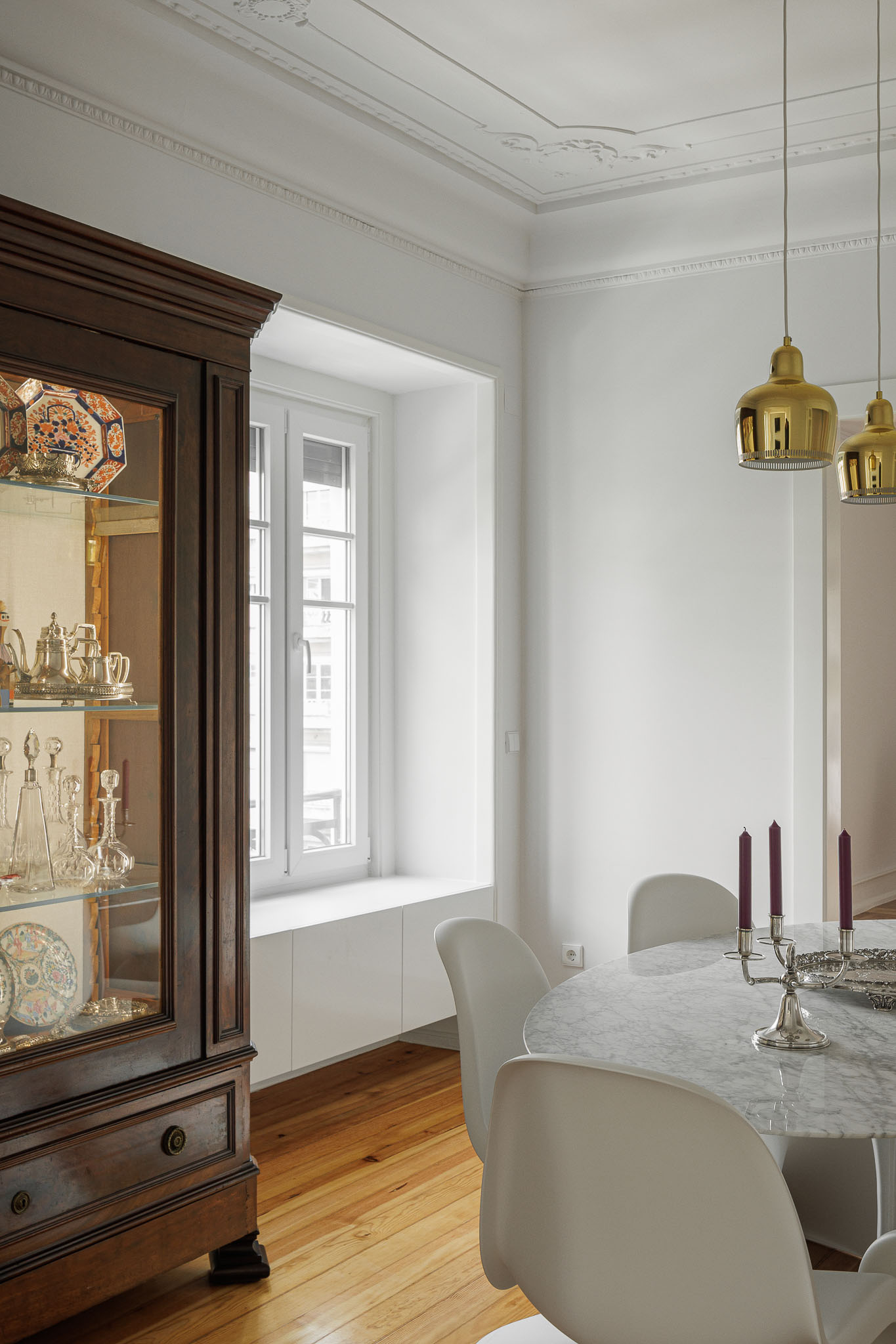 Sala de jantar: Vitrine clássica, mesa de mármore com cadeiras brancas e candeeiros dourados pendentes. — Apartamento AN arquitetura NMDARQ – Nuno Miguel Dias, Arquitecto em Lisboa