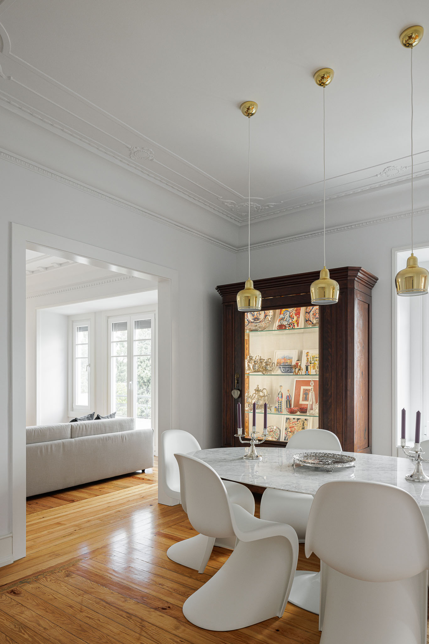 Sala de jantar: Mesa com cadeiras brancas, vitrine antiga e vista para a sala de estar com sofá cinzento. — Apartamento AN arquitetura NMDARQ – Nuno Miguel Dias, Arquitecto em Lisboa
