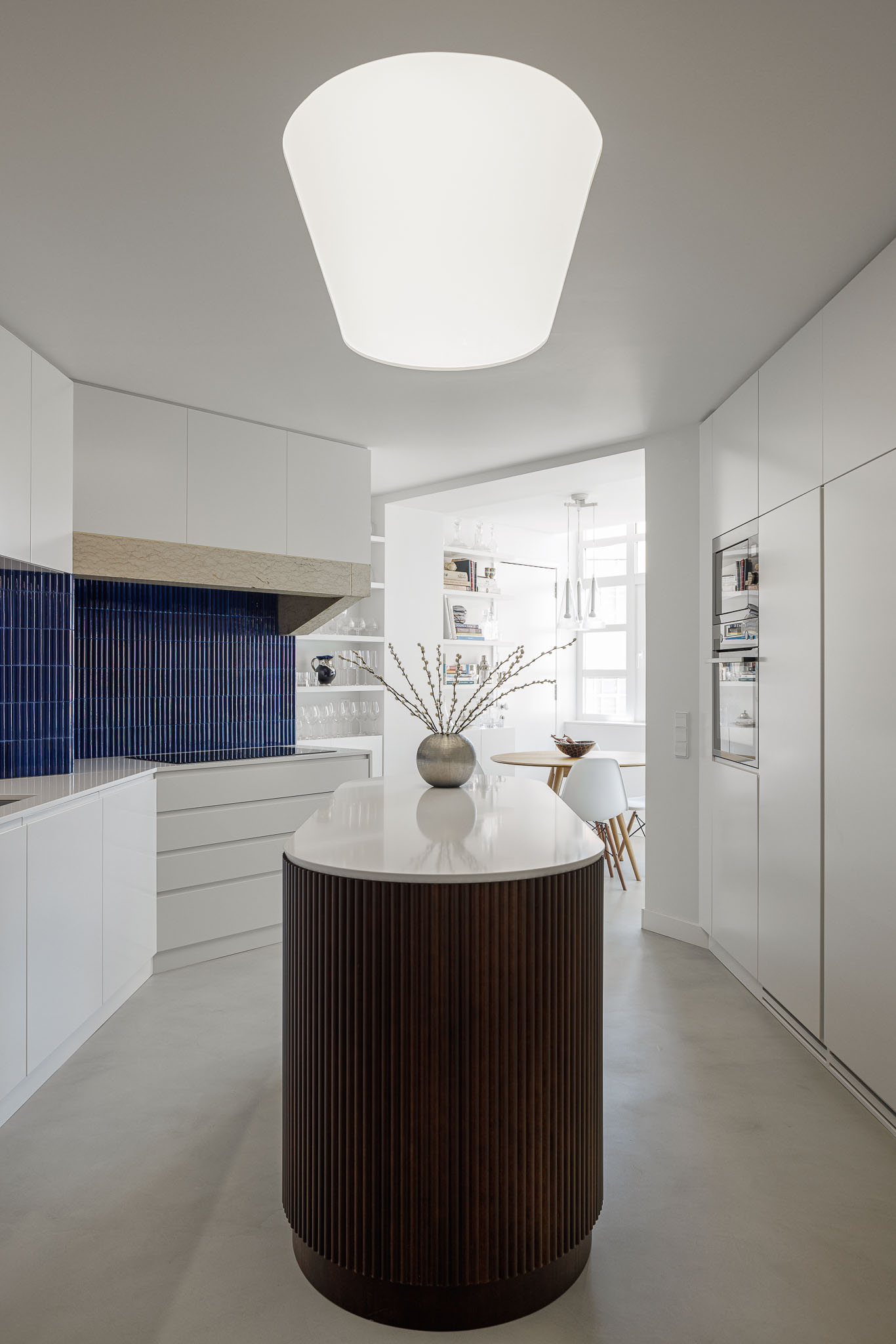 Cozinha: Ilha central com revestimento em madeira escura, armários brancos e backsplash em azulejo azul. — Apartamento AN arquitetura NMDARQ – Nuno Miguel Dias, Arquitecto em Lisboa