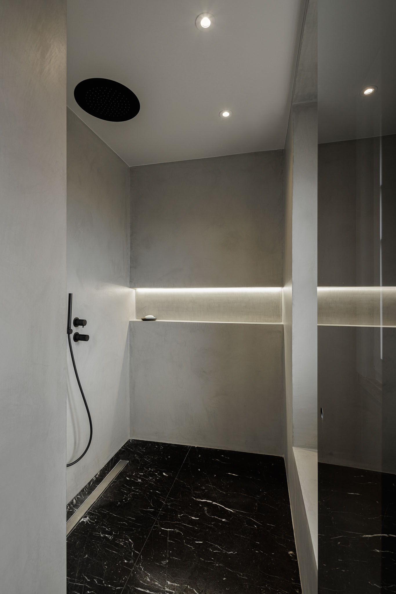 Casa de banho: Cabine de duche com revestimento em betão aparente e pavimento em mármore preto. — Apartamento AN arquitetura NMDARQ – Nuno Miguel Dias, Arquitecto em Lisboa