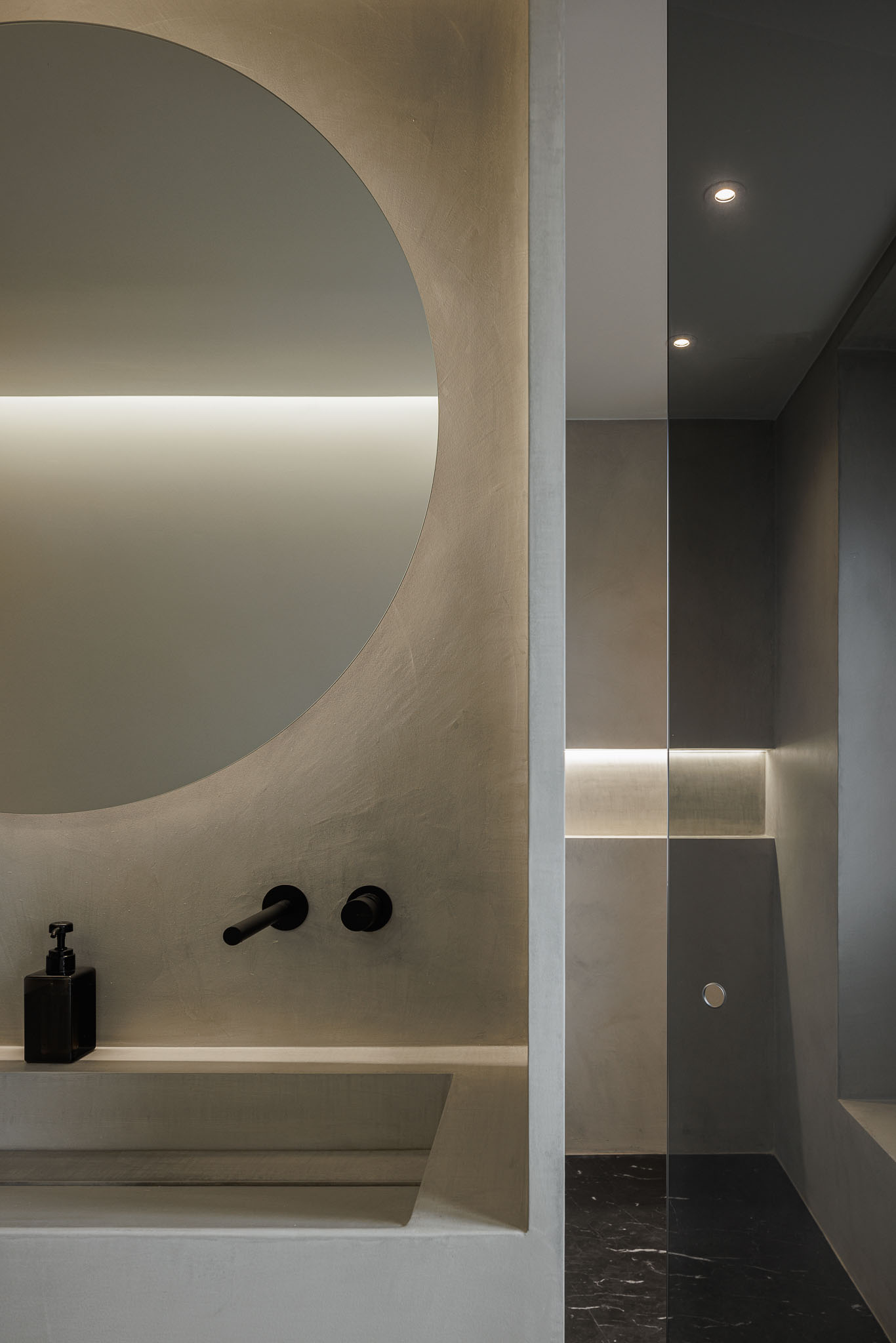 Casa de banho: Detalhe do lavatório em betão aparente, espelho redondo e cabine de duche. — Apartamento AN arquitetura NMDARQ – Nuno Miguel Dias, Arquitecto em Lisboa