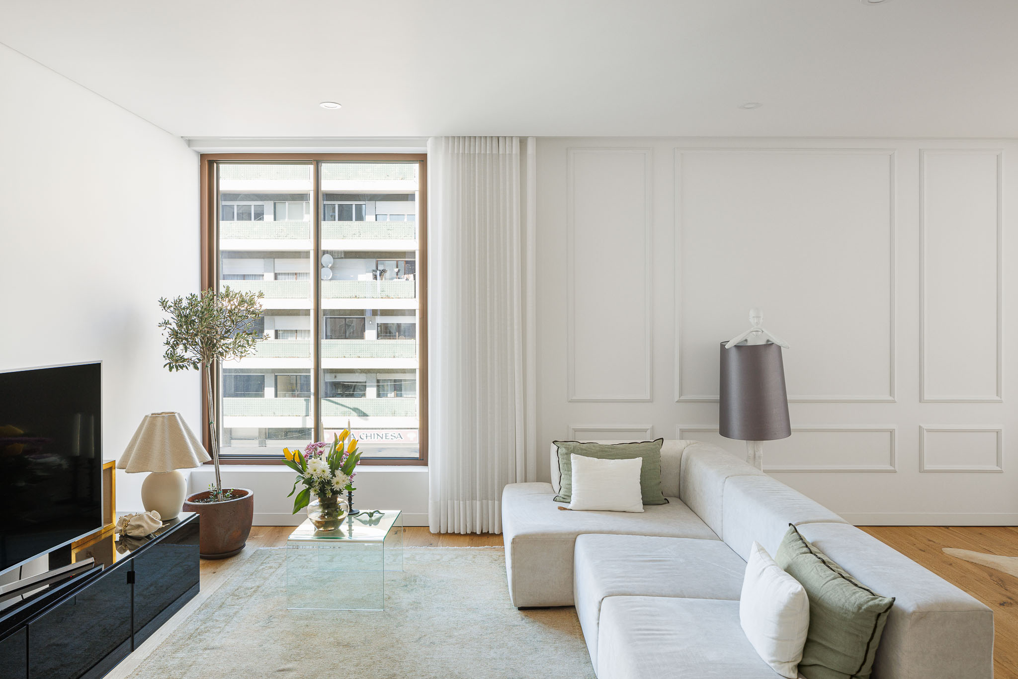 Sala de estar: Espaço luminoso com sofá modular cinza, alcatifa clara e pavimento em madeira. — 5ª Avenida arquitetura Mário Alves Arquitecto em Aveiro