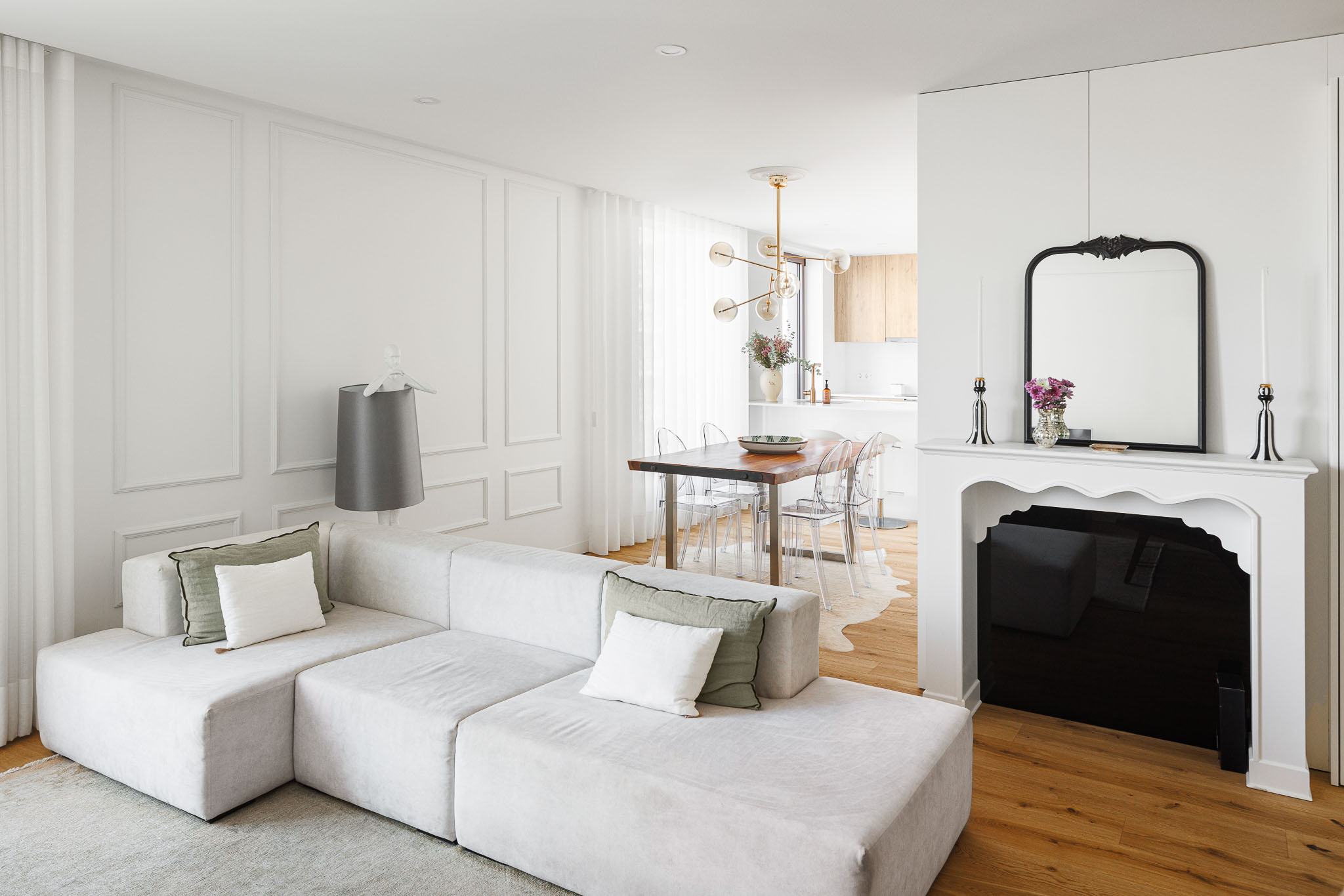 Sala de estar: Perspectiva da sala de estar para a sala de jantar e cozinha, com lareira decorativa. — 5ª Avenida arquitetura Mário Alves Arquitecto em Aveiro