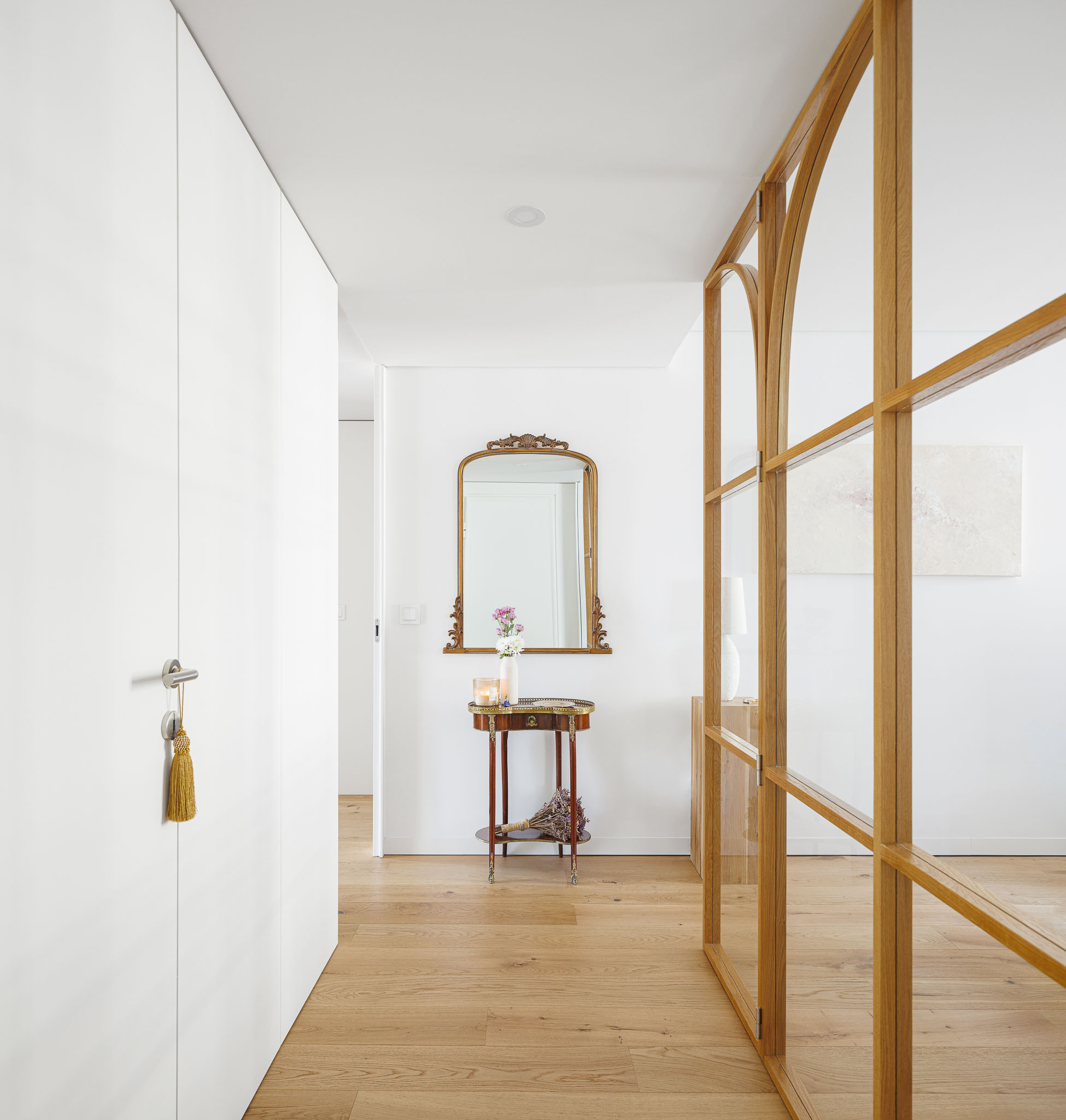 Corredor: Espaço de circulação com pavimento em madeira, espelho dourado e divisória em vidro e madeira. — 5ª Avenida arquitetura Mário Alves Arquitecto em Aveiro