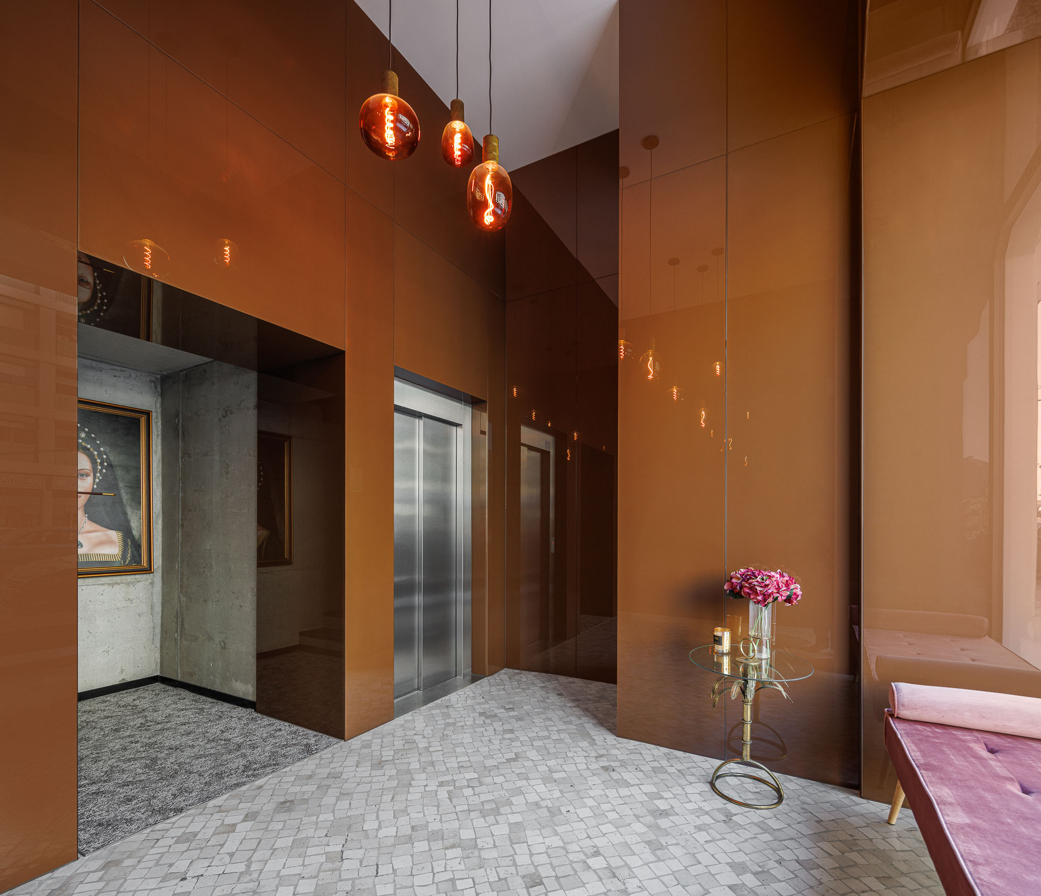 Hall de entrada: Elevador em aço inoxidável, paredes espelhadas em bronze e pavimento em calçada. — 5ª Avenida arquitetura Mário Alves Arquitecto em Aveiro