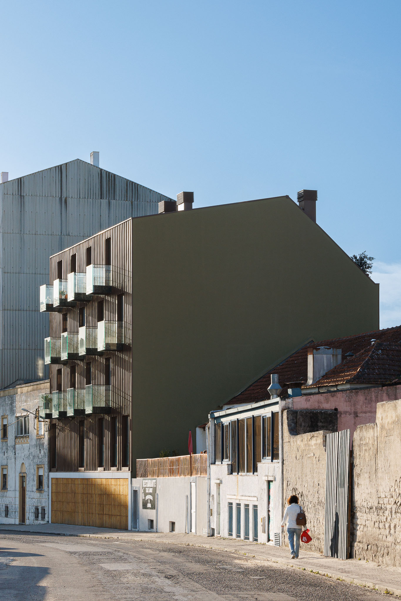 Fachada: Vista lateral do edifício renovado, mostrando a fachada moderna em cobre e a empena cega. — 5ª Avenida arquitetura Mário Alves Arquitecto em Aveiro
