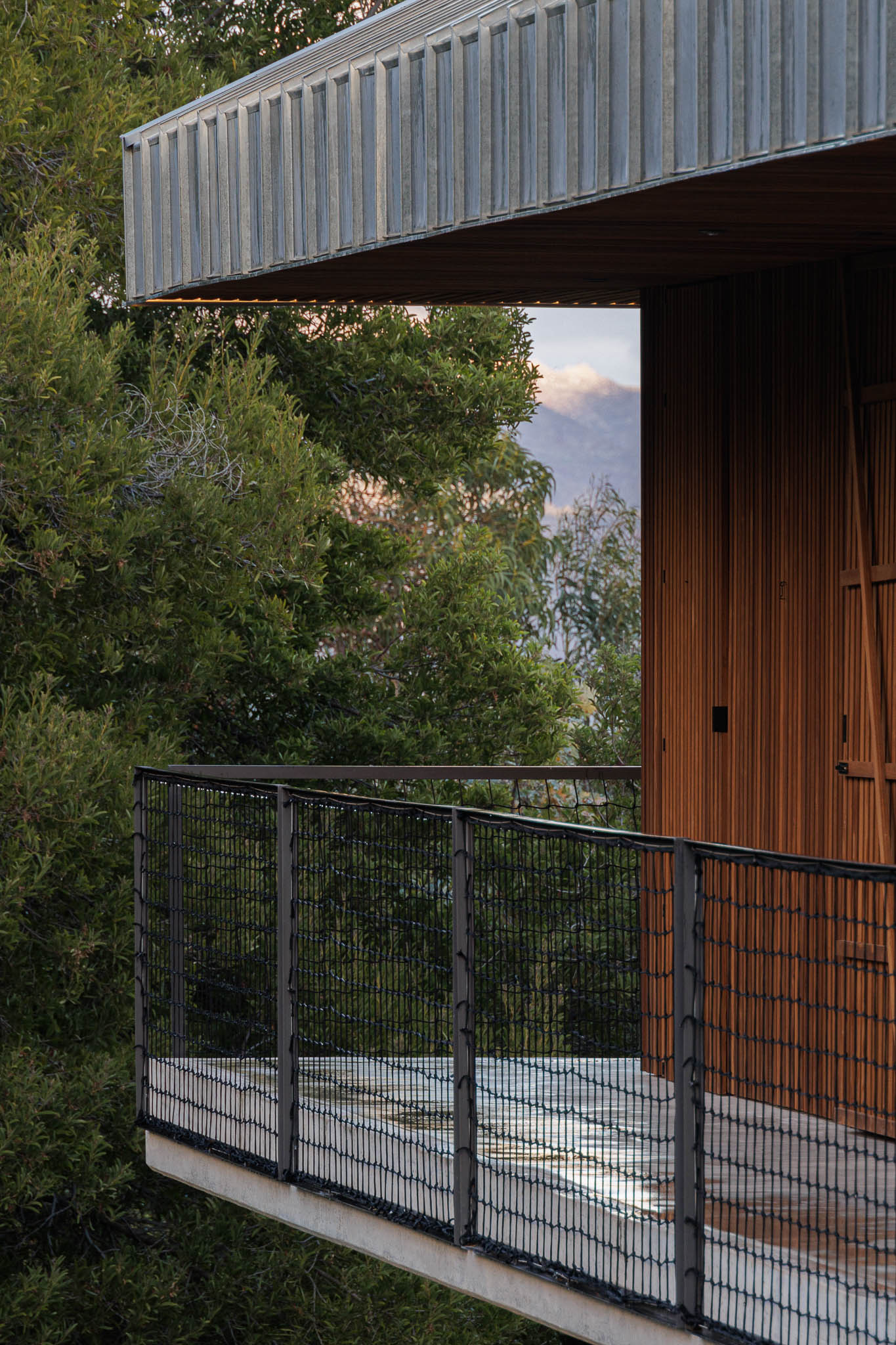 Varanda: Guarda em rede metálica preta e revestimento em madeira vertical. — The Vagar – Country House arquitetura David Bilo Arquitectos e Filipe Pina Arquitectura em Belmonte
