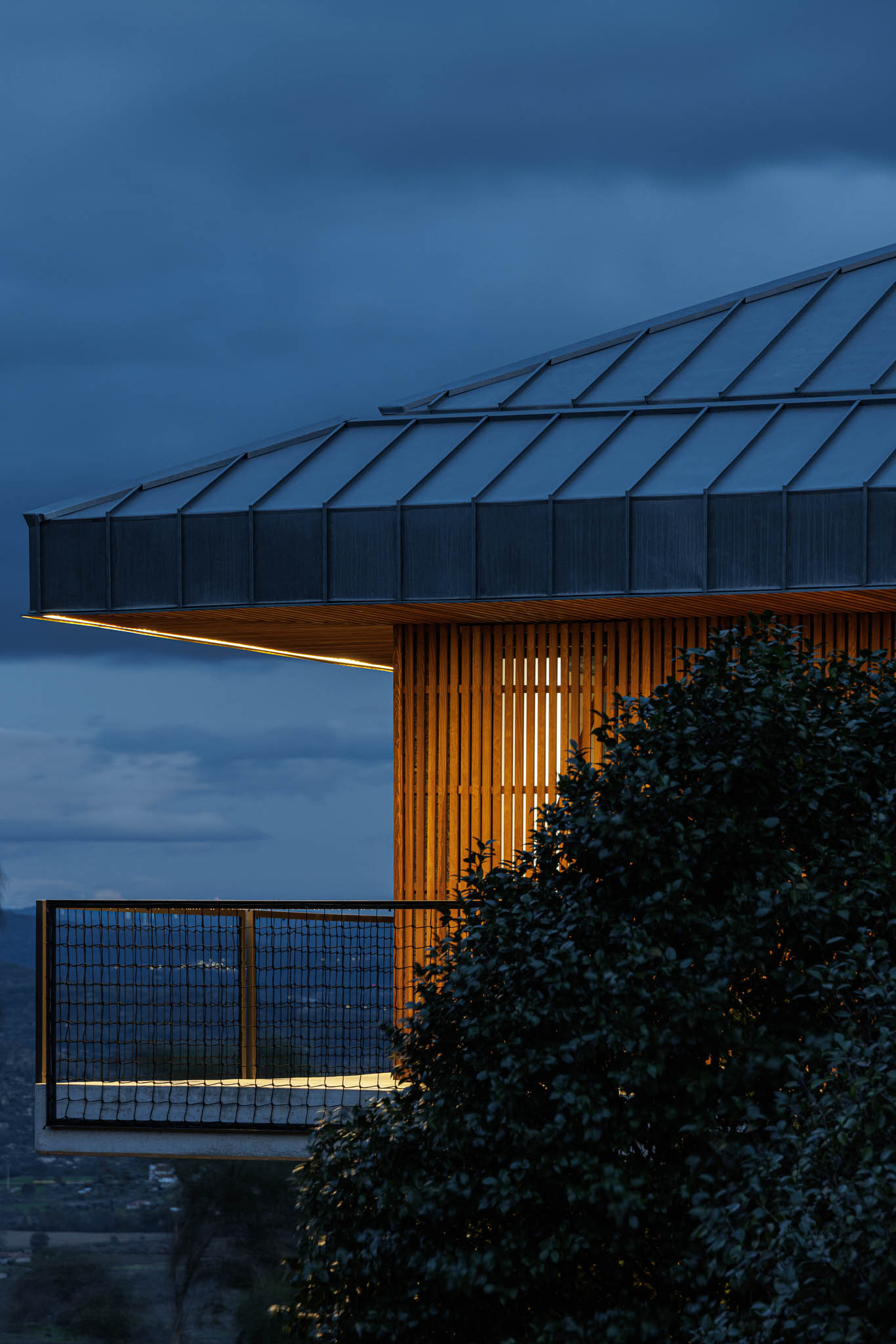 Exterior: Vista noturna da casa de campo com telhado metálico e iluminação exterior. — The Vagar – Country House arquitetura David Bilo Arquitectos e Filipe Pina Arquitectura em Belmonte